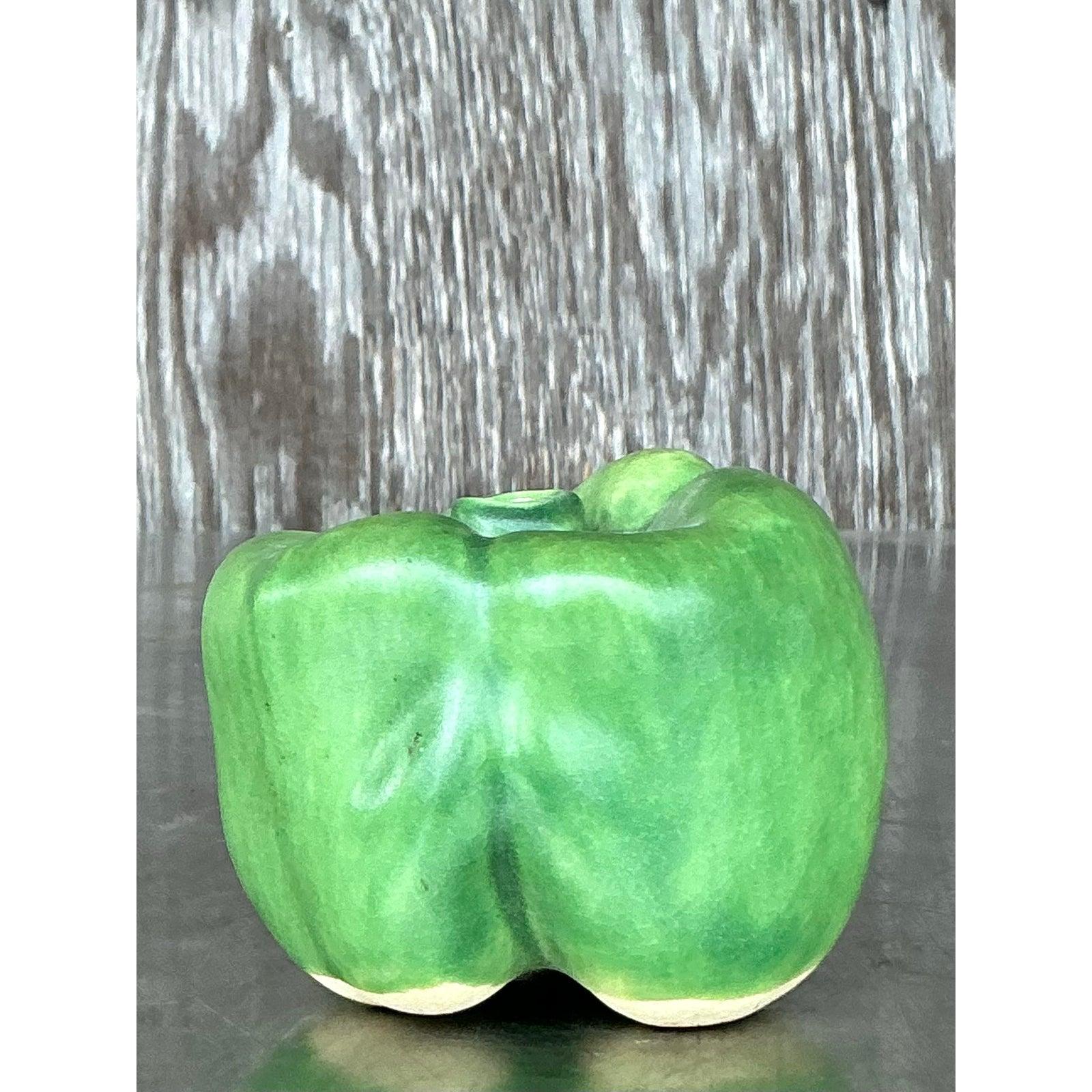 Aggiungi un pizzico di fascino giocoso al tuo arredamento con questa scultura di peperone in ceramica smaltata vintage. Modellato a mano e rifinito con una vivace smaltatura verde, questo stravagante pezzo cattura la forma e la consistenza naturale