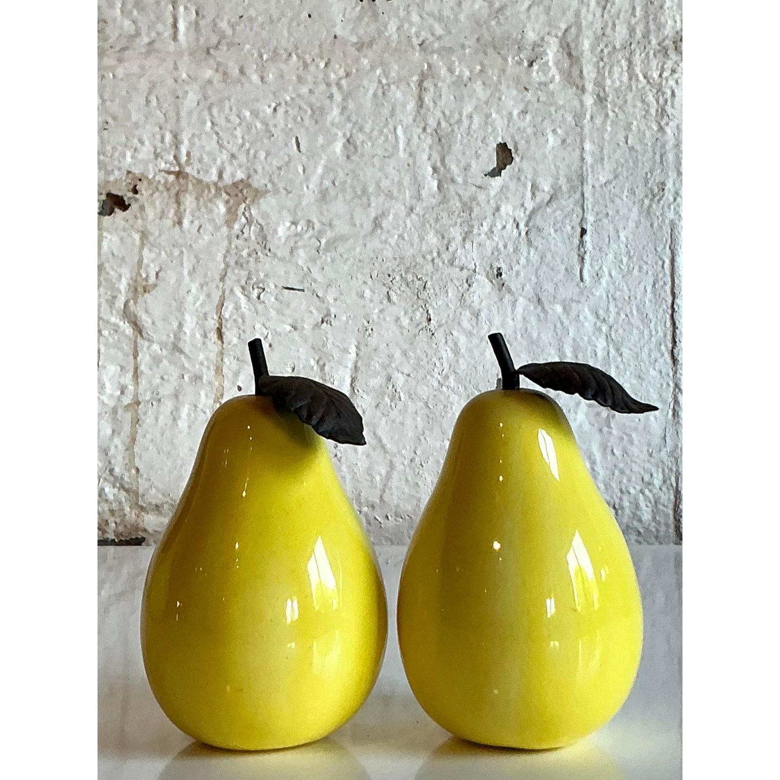 Introduci un delizioso tocco di colore e un fascino stravagante con questo affascinante set di due pere in ceramica smaltata vintage. Ogni pera vanta una vibrante finitura gialla lucida che cattura e riflette la luce, creando un allegro punto focale