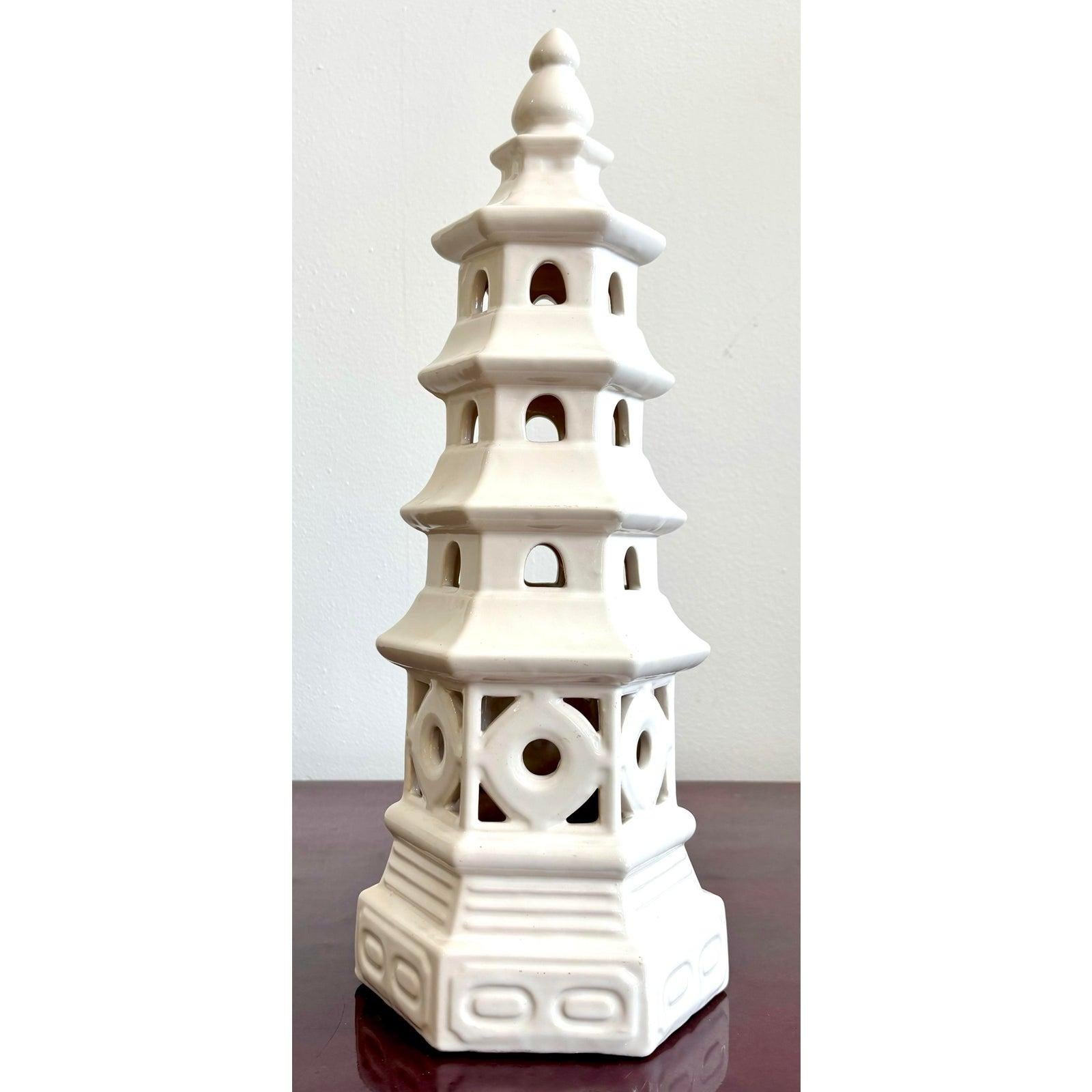Questa scultura pagoda in ceramica bianca è un grazioso accento architettonico che trae ispirazione dal design tradizionale dell'Asia orientale. Con i suoi livelli a gradoni, le finestre ad arco e la base geometrica traforata, dona un senso di ritmo