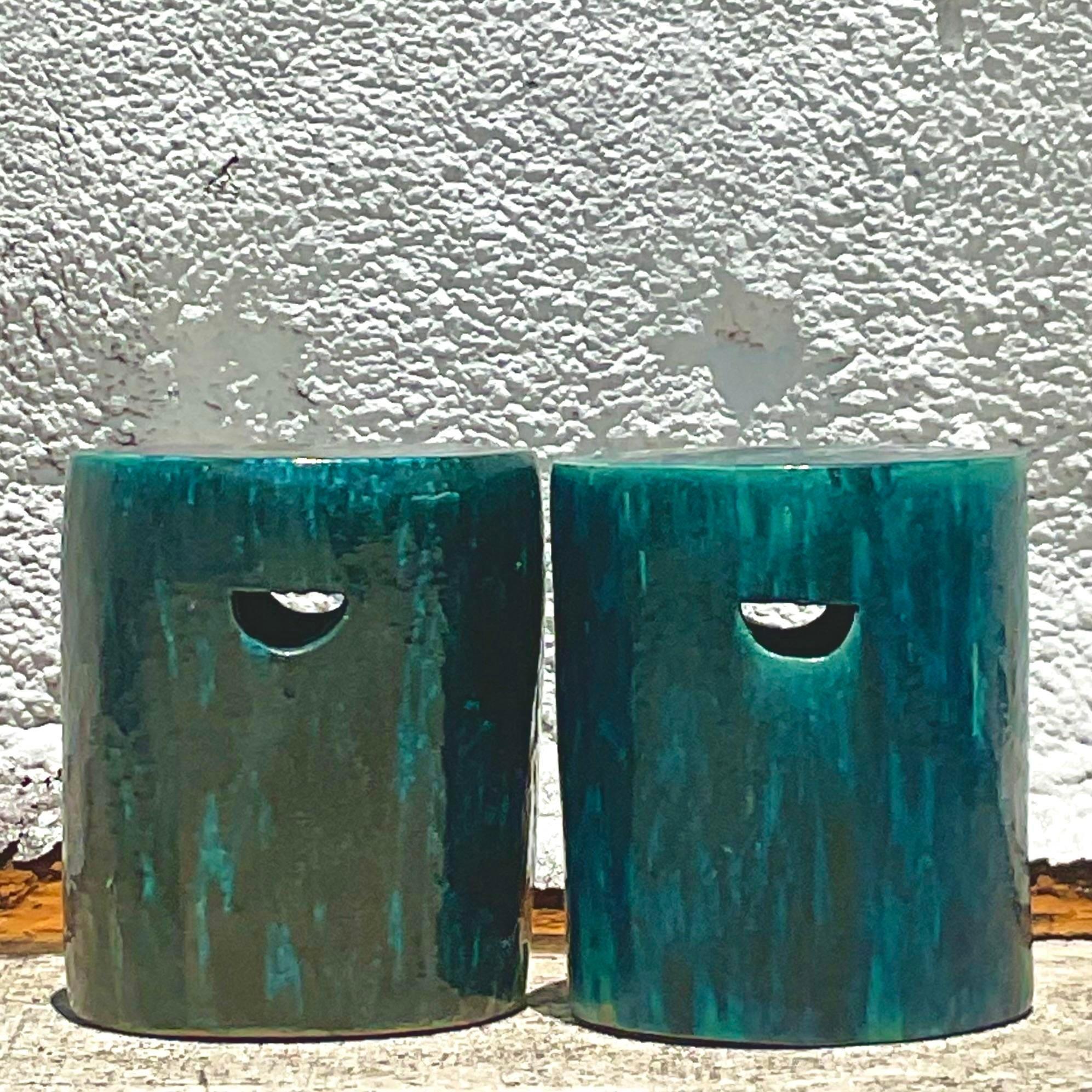 An exceptional pair of vintage Boho stools. A chic glazed ceramic in brilliant blues and greens. A simple shape with two half round cutouts as handles. Perfect indoors or outside in a covered area. Acquired from a Palm Beach estate.