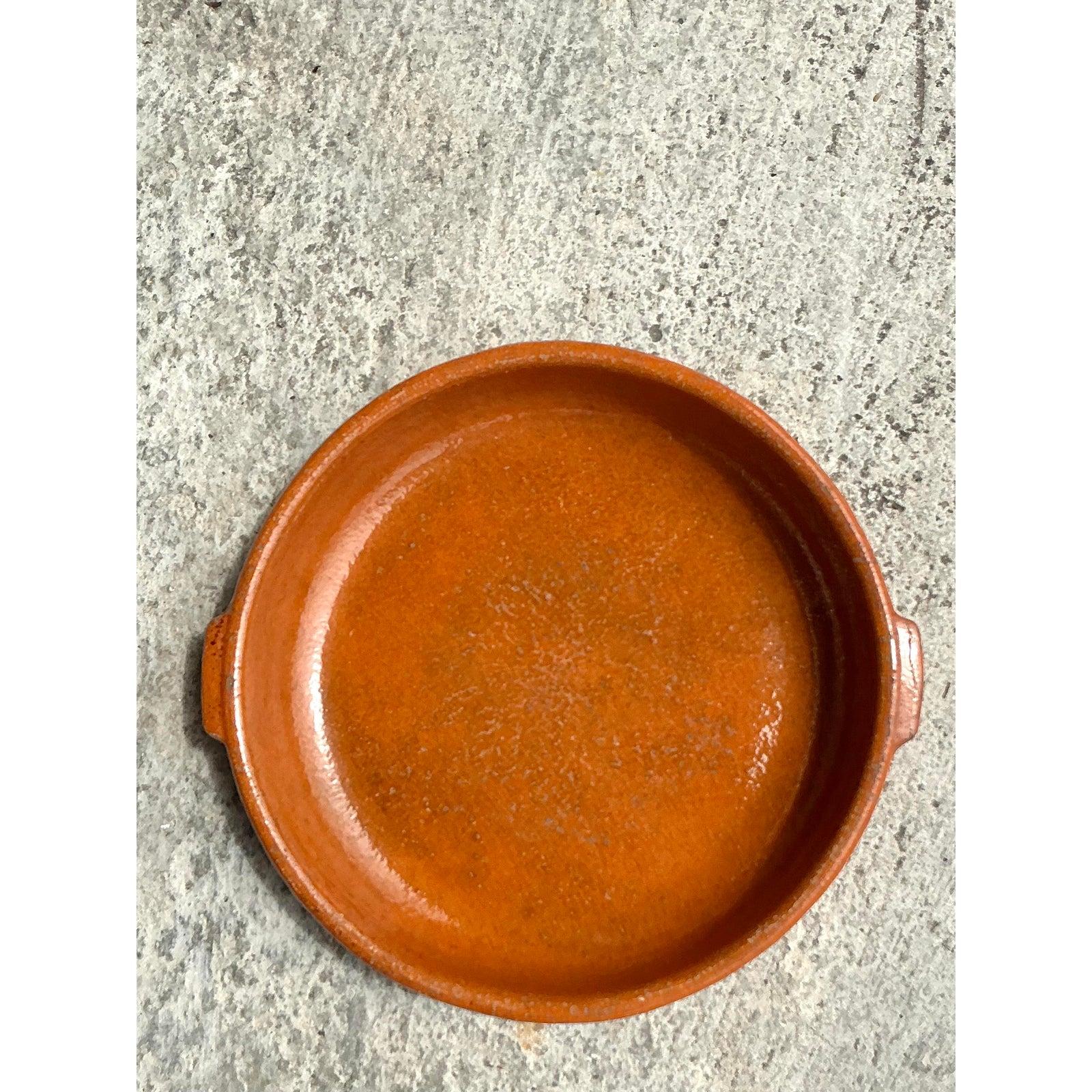 Esta asombrosa bandeja de cerámica boho vintage luce un rico acabado esmaltado a mano en un cálido tono terracota. Su forma suavemente curvada y su robusta artesanía resaltan su encanto artesanal, convirtiéndola en una pieza versátil tanto para uso