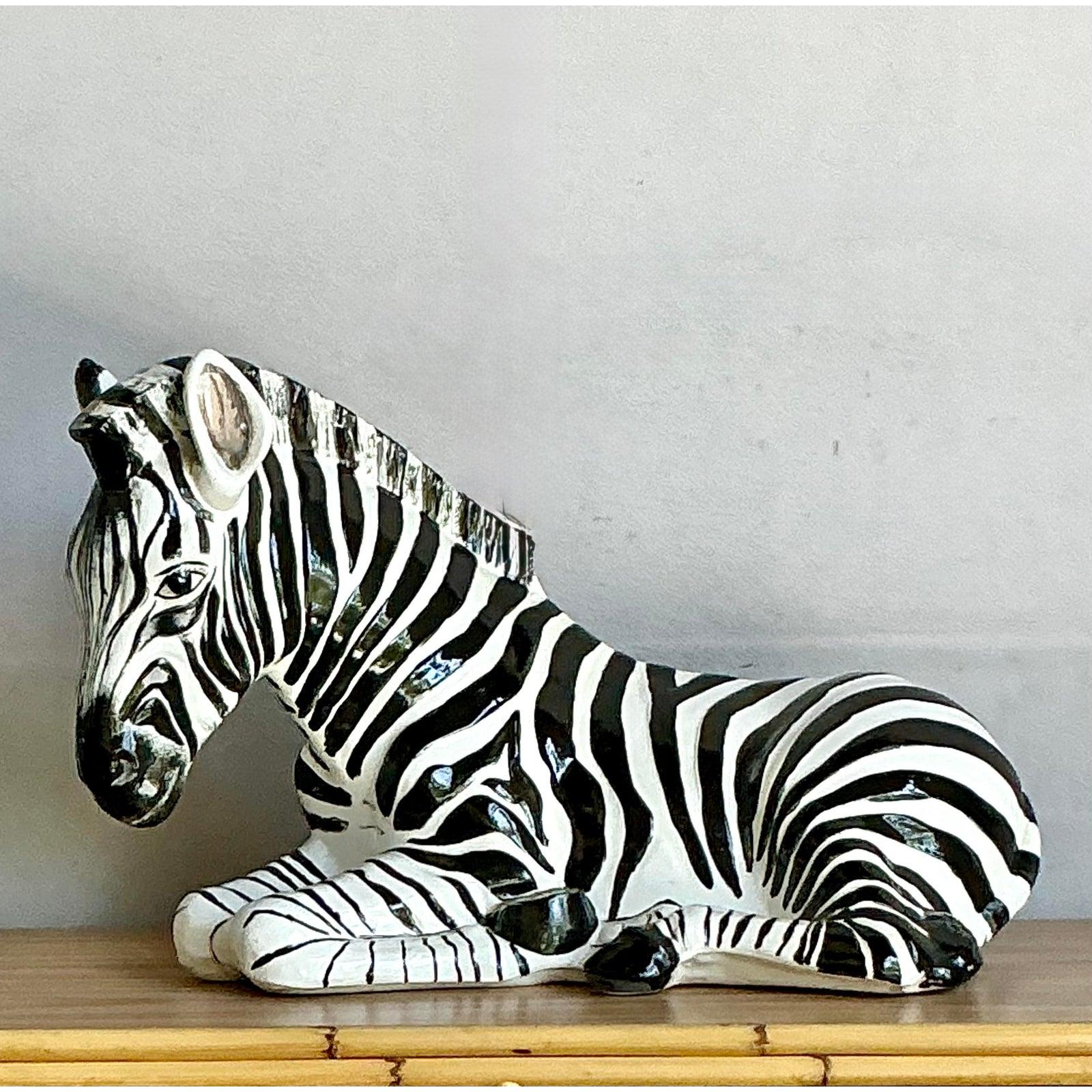 Dai un tocco di selvaggia raffinatezza ai tuoi interni con questa accattivante scultura zebrata in ceramica vintage. Questa zebra reclinabile, dalle dimensioni meravigliose, si fa notare per le sue classiche strisce bianche e nere dipinte a mano e
