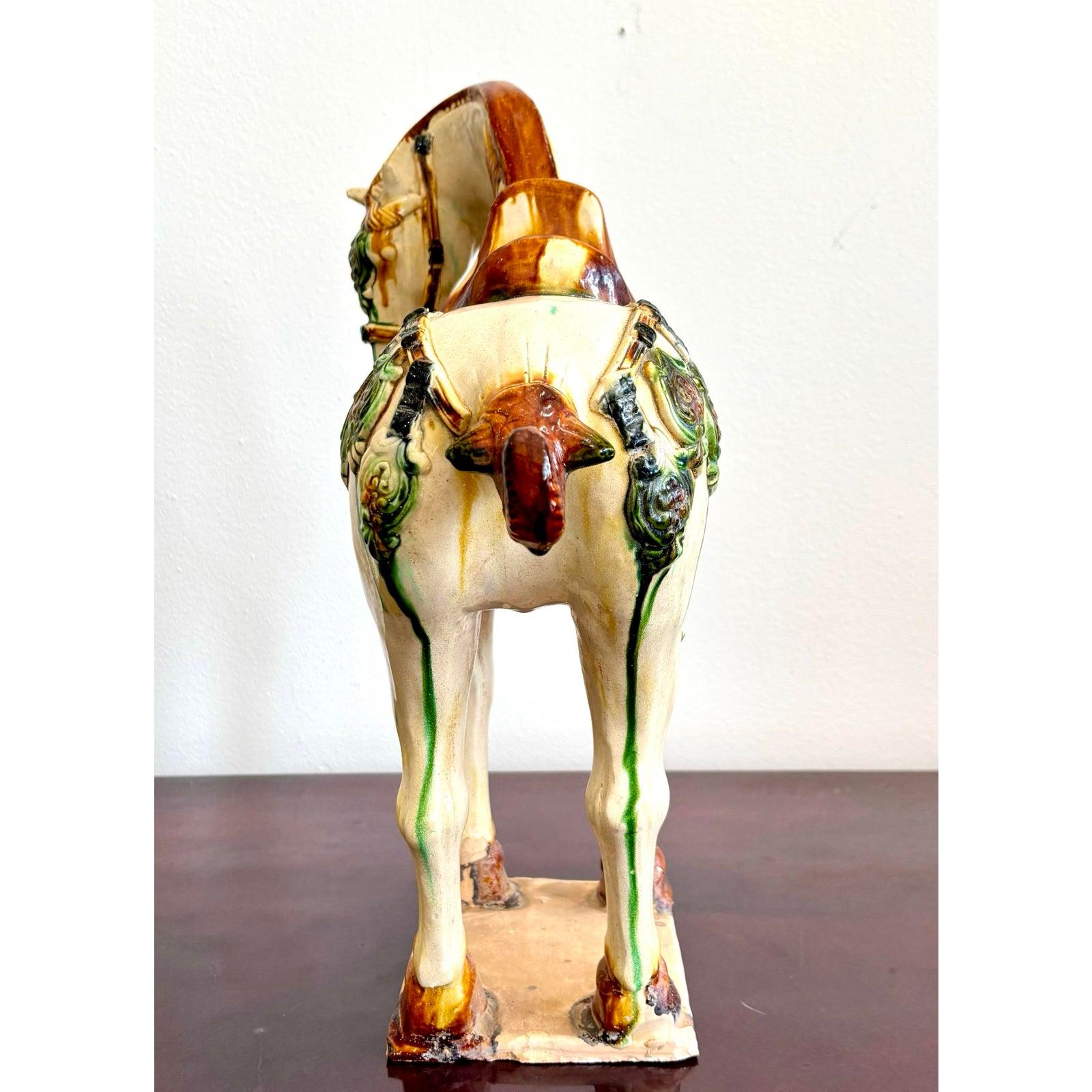 Este caballo de cerámica esmaltada canaliza el espíritu regio del arte de la antigua Tang Dynasty con una paleta sorprendentemente rica de ámbar, jade y crema. Su silla de montar fluida y sus adornos parecen fundirse en el cuerpo como un color