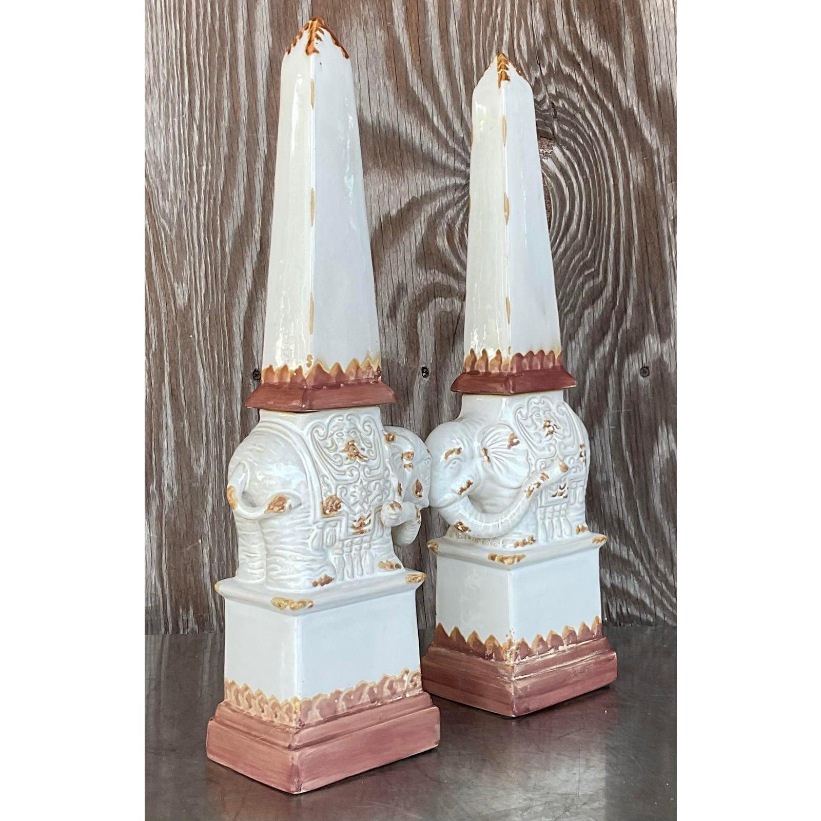 A stunning pair of vintage glazed terra cotta obelisks. A fun elephant design with trunks up for good luck. Acquired from a Palm Beach estate.