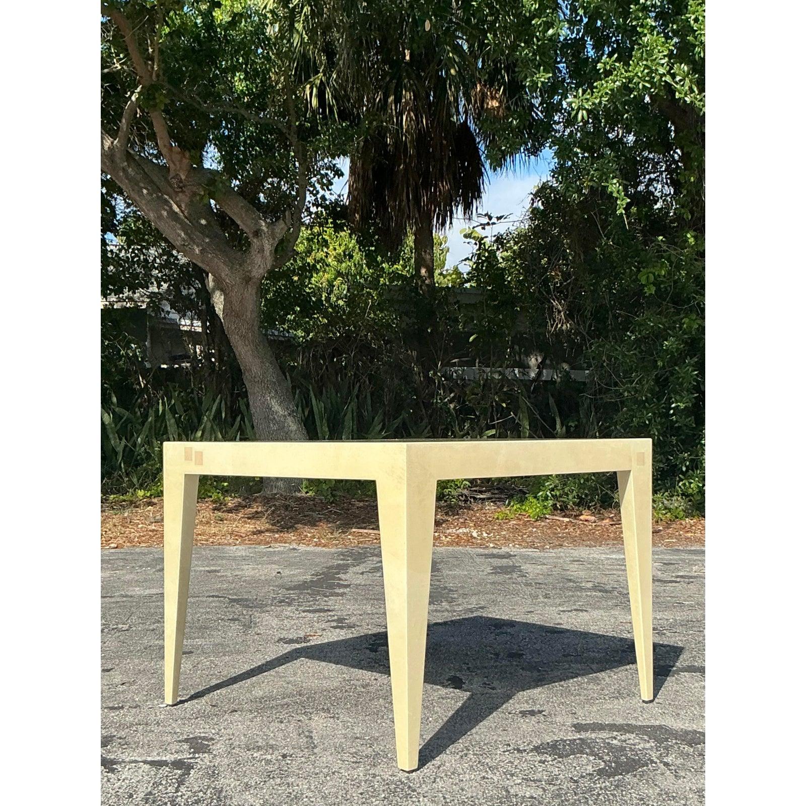 Ajoutez une sophistication audacieuse à votre espace avec cette table de jeu boho vintage, magistralement fabriquée dans le style de Karl Springer. Enveloppé d'un placage parcheminé en peau de chèvre luxueuse, le plateau de table carré et les pieds