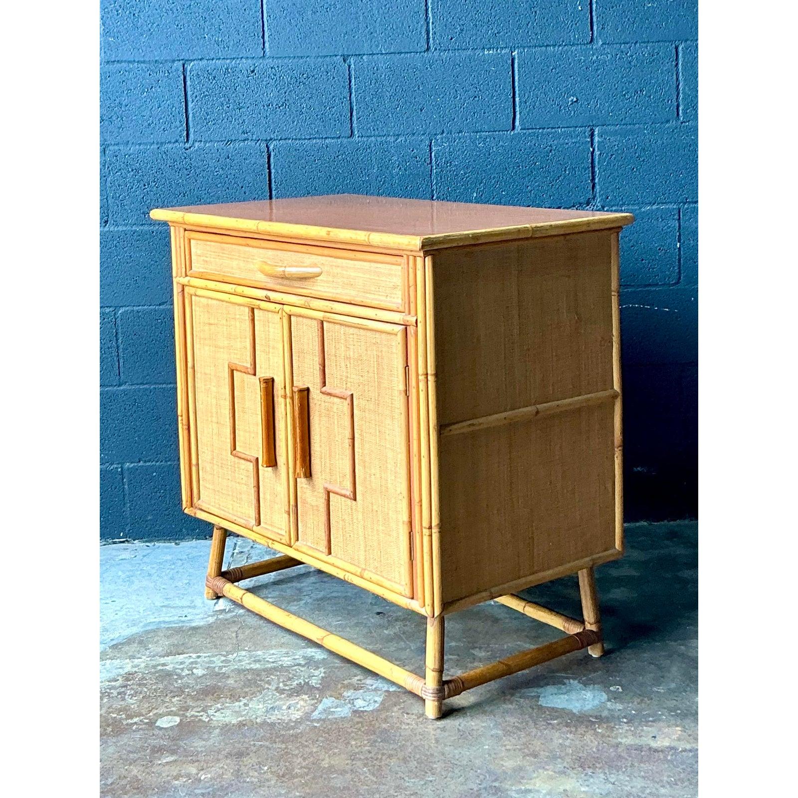 This attractive storage cabinet seamlessly blends tropical materiality with tailored Mid-Century Modern utility, embodying the resort-chic style of the 1970s. The structure is skillfully crafted from natural rattan and bamboo, featuring a top