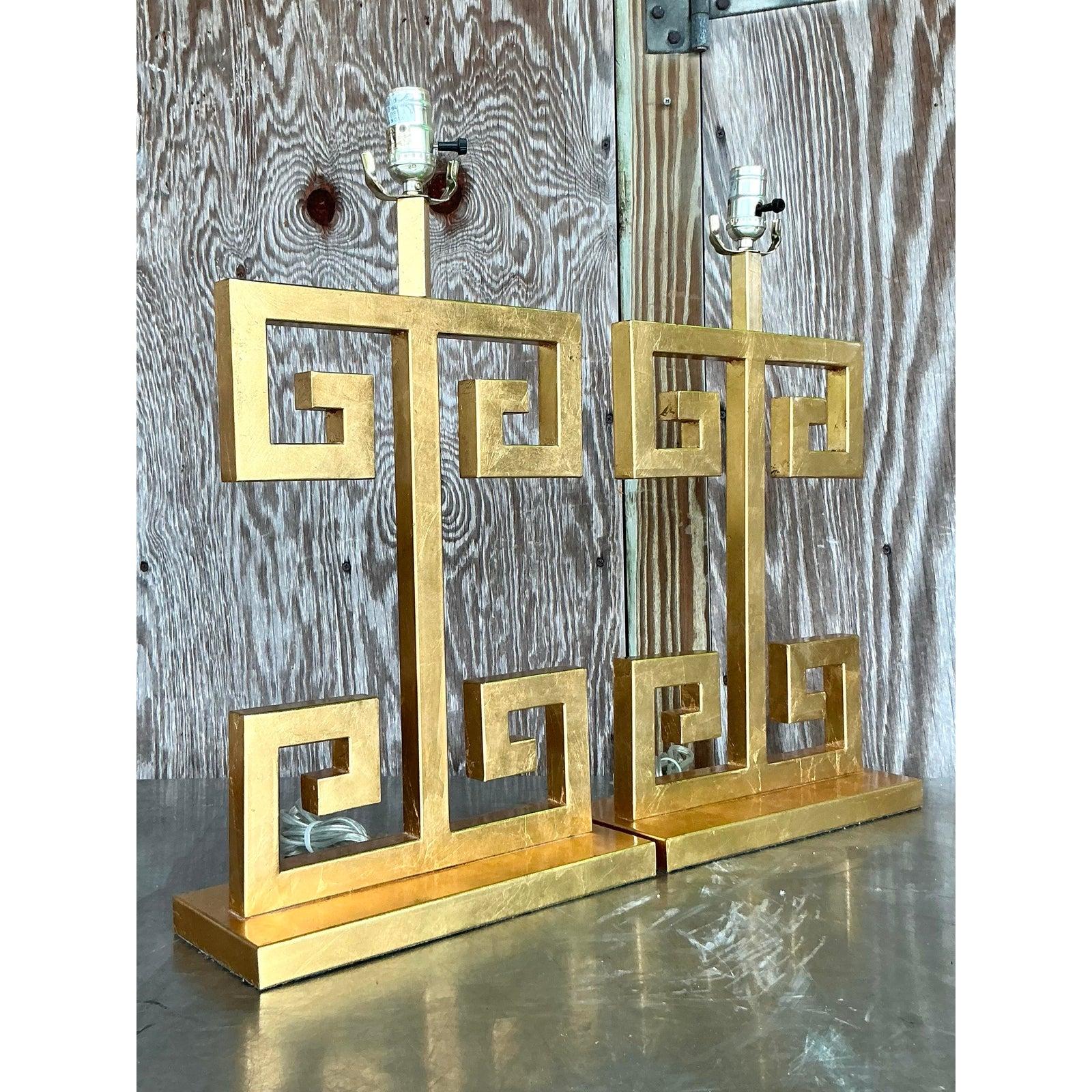 Channel the timeless glamour of Hollywood Regency with this spectacular pair of vintage gilt table lamps. Defined by their bold, architectural form, each lamp showcases the iconic Greek Key motif, creating a stunning openwork design that is both