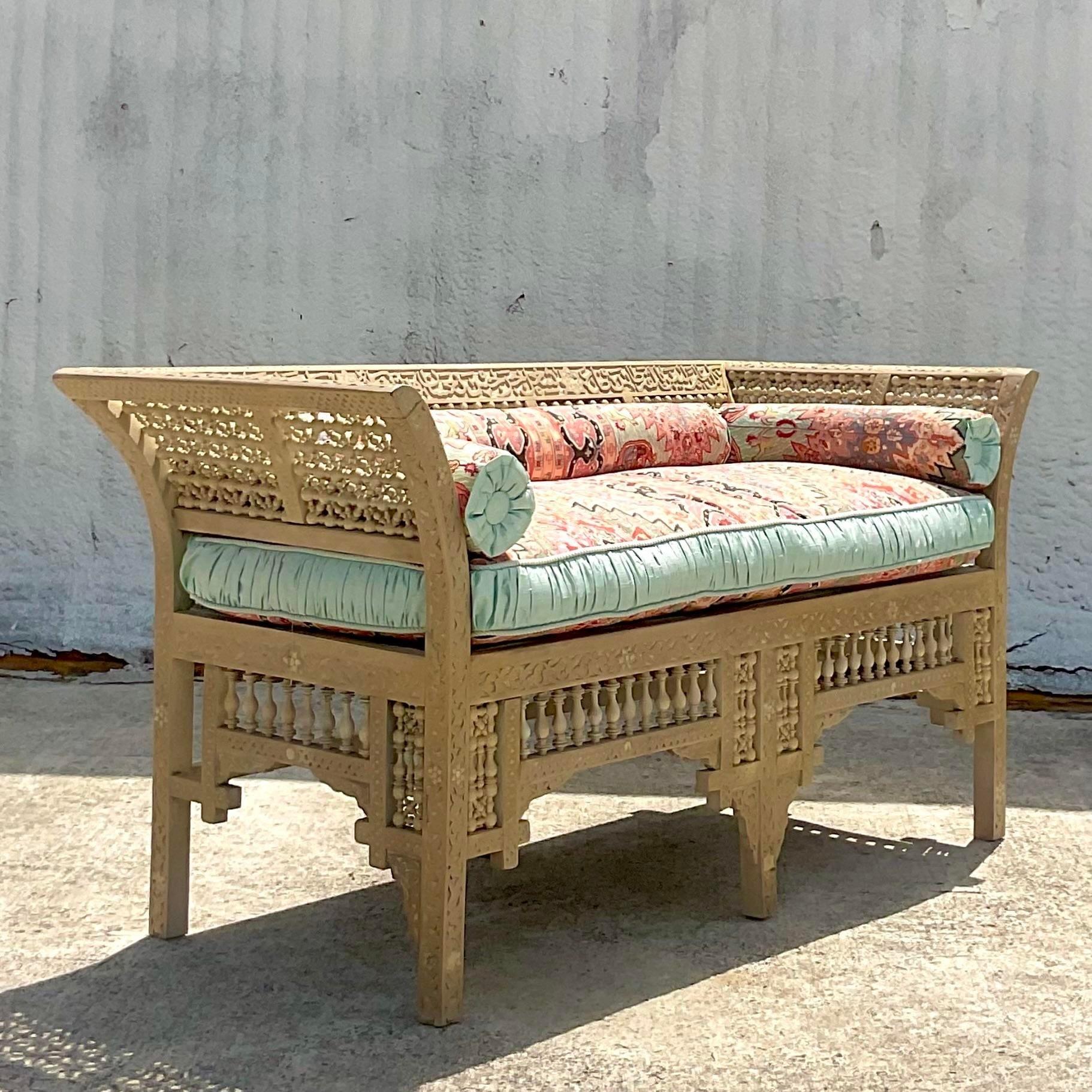 A stunning vintage Boho hand carved teak loveseat. A chic cerused finish on the classic Anglo Indian design. Beautifully upholstered in a gorgeous paisley with a ruched trim. A real showstopper. Acquired from a Palm Beach estate.