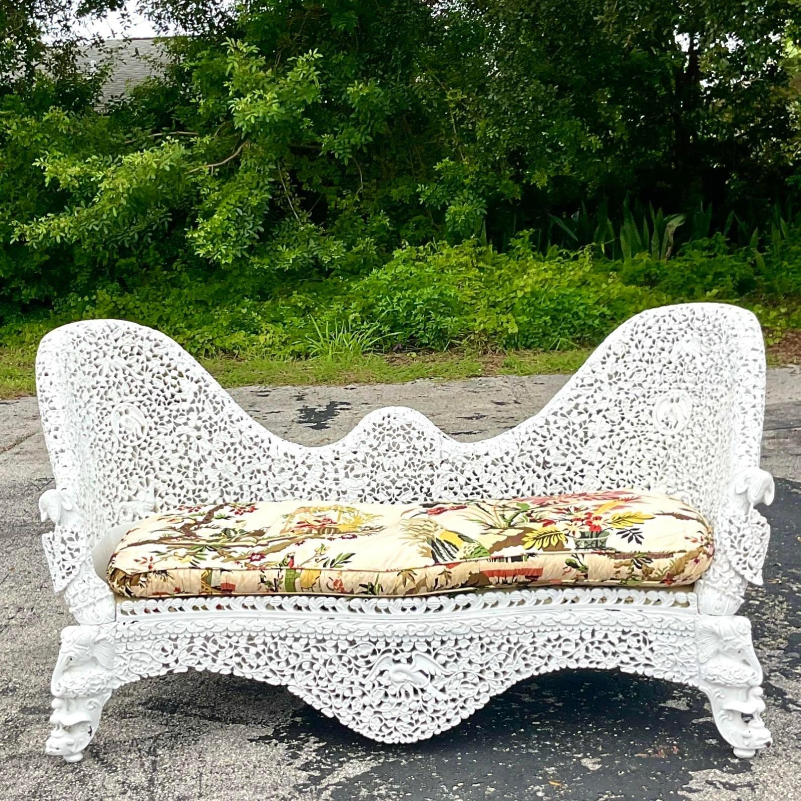 An extraordinary vintage Boho wood sofa. A hand carved Burmese gem with the more intricate carved detail. A sweeping high back in a gloss white finish. A fabulous Chinoiserie printed cushion. Acquired from a beautiful Palm Beach estate.