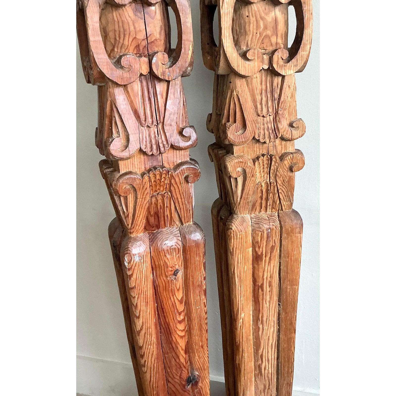 Instantly elevate your interior with the dramatic presence of this stunning pair of vintage hand-carved wood columns. Each column is a testament to masterful woodworking, featuring deeply carved acanthus leaf motifs and bold scroll details that