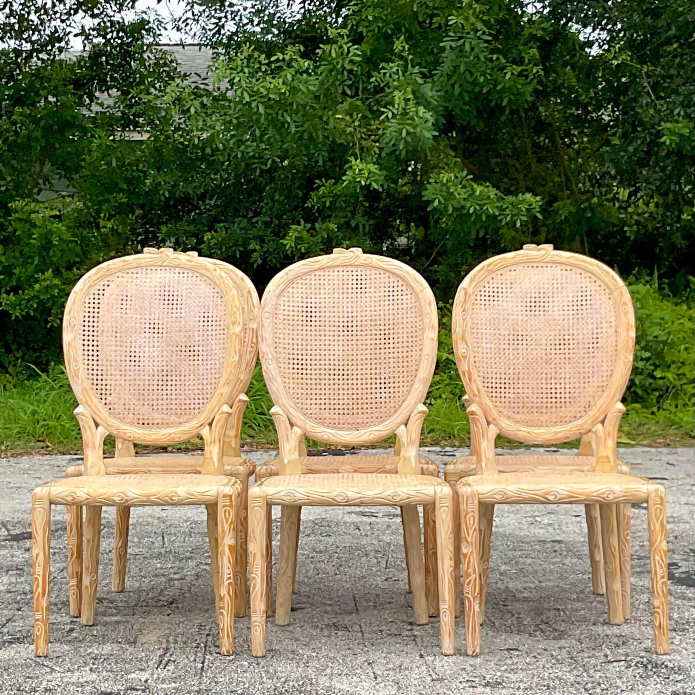 A fabulous set of 6 vintage Boho dining chairs. Beautiful hand carved Faux Bois design with a chic cerused finish. An inset cane seat and back medallion. Acquired from a Palm Beach estate