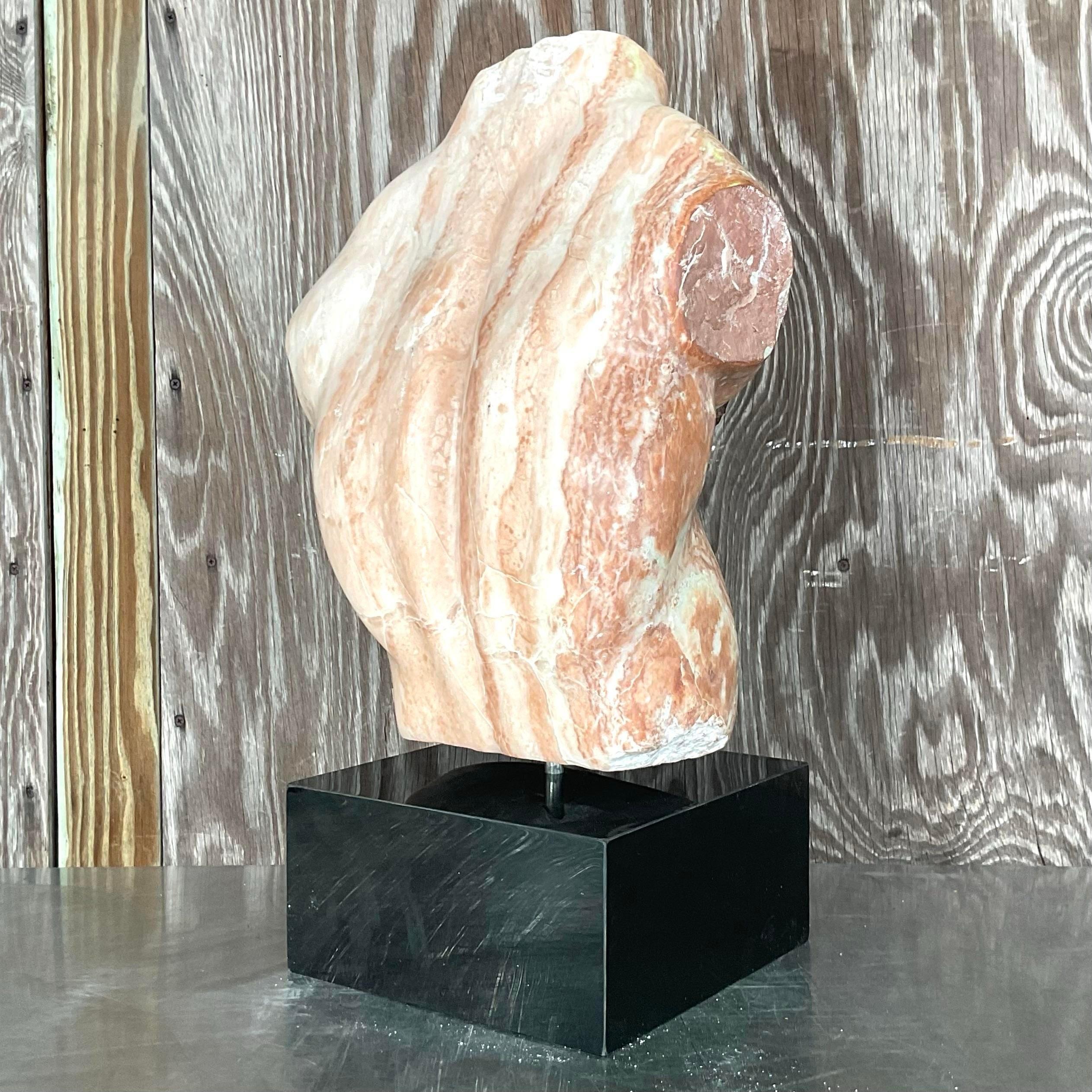 Vintage bohemian marble sculpture of a male torso with multicolored streaks going down vertically. This dynamic piece is attached to a black stone pedestal. Acquired from a Palm Beach estate.