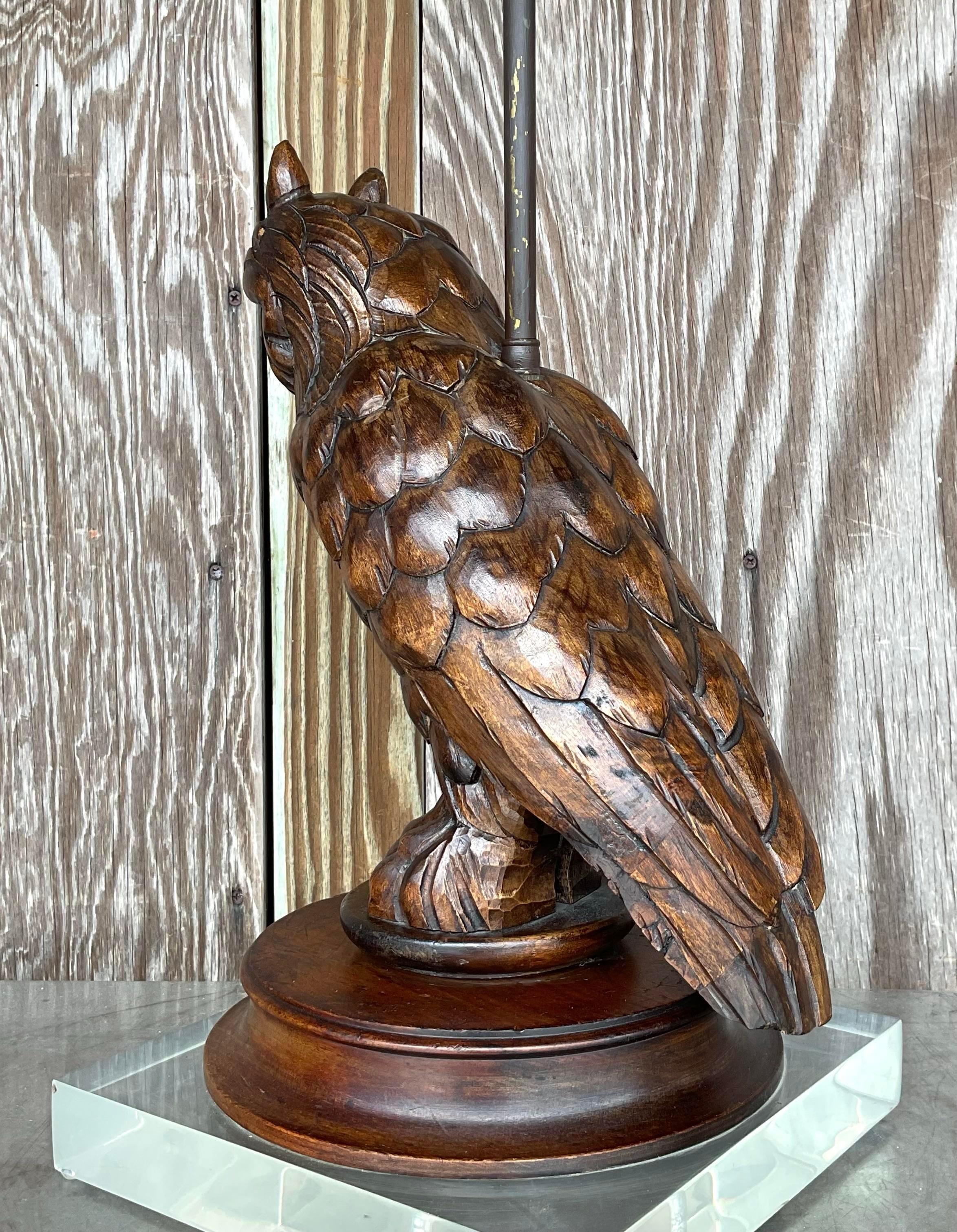 Questa squisita lampada vintage presenta un gufo splendidamente intagliato a mano appollaiato in cima a una base di lucite trasparente, fondendo l'arte naturale con l'eleganza moderna. Il ricco legno scuro del gufo contrasta in modo sorprendente con