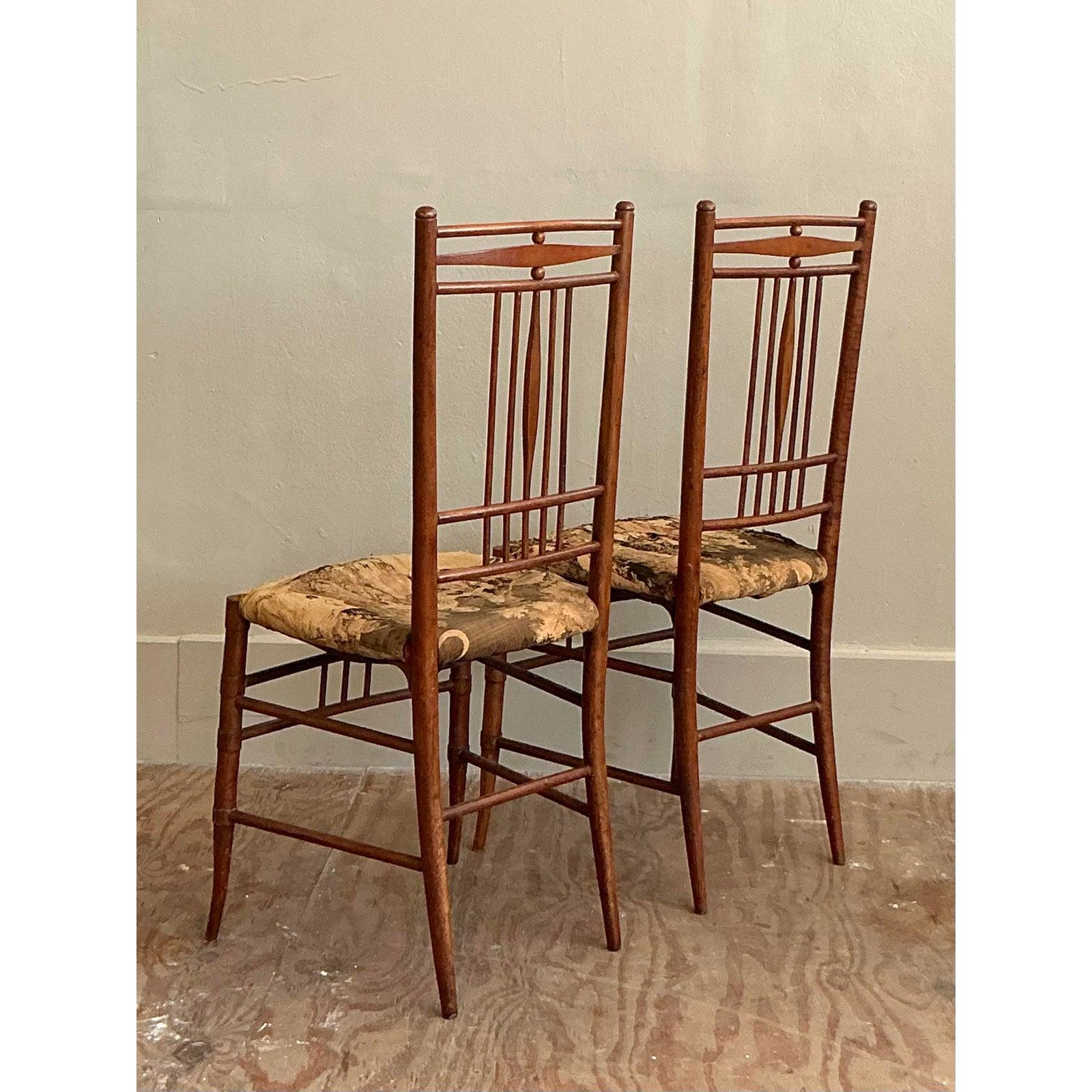 A delightful pair that perfectly captures the intersection of Chinoiserie elegance and European tradition. These vintage dining chairs feature delicately turned wood frames crafted to mimic the timeless look of bamboo—a hallmark of the sophisticated