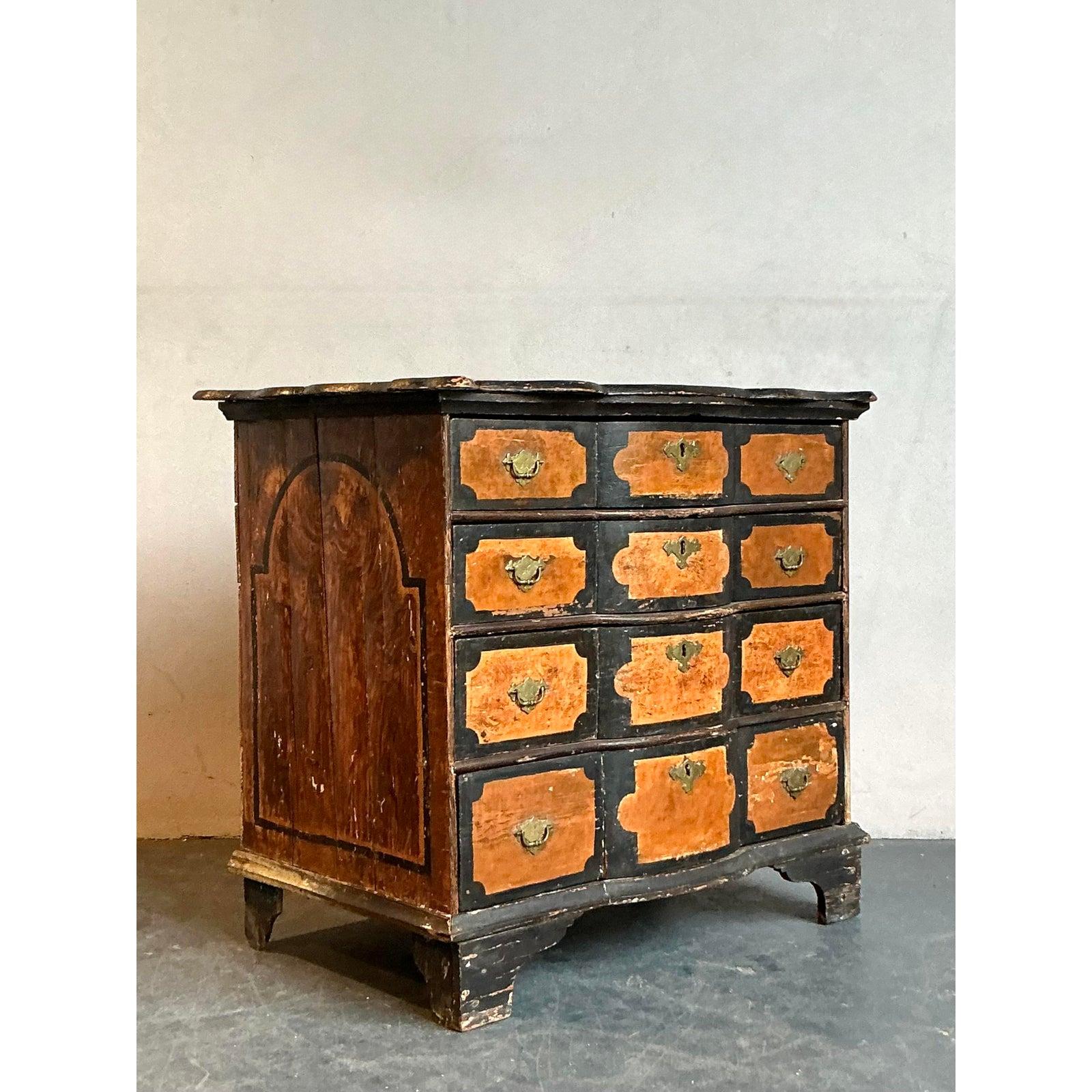 Scopri il fascino unico di questa cassettiera Vintage Boho dipinta a mano, un pezzo accattivante che emana carattere storico e fascino artistico. Sebbene sia stato progettato per apparire come un mobile a nove cassetti, questo pezzo intelligente