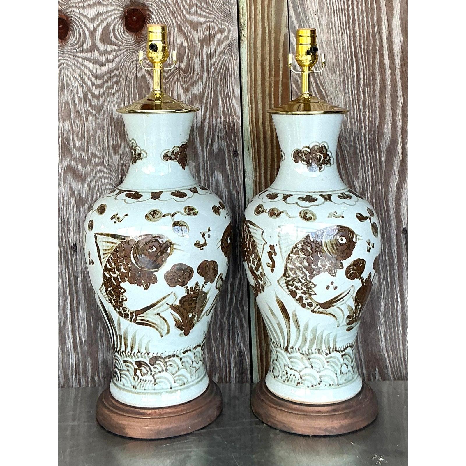 Illuminate your home with this enchanting pair of Vintage Boho Hand Painted Koi Lamps, a captivating blend of artistic elegance and natural symbolism. Each lamp showcases exquisite hand-painted koi fish gracefully swimming amidst stylized waves and