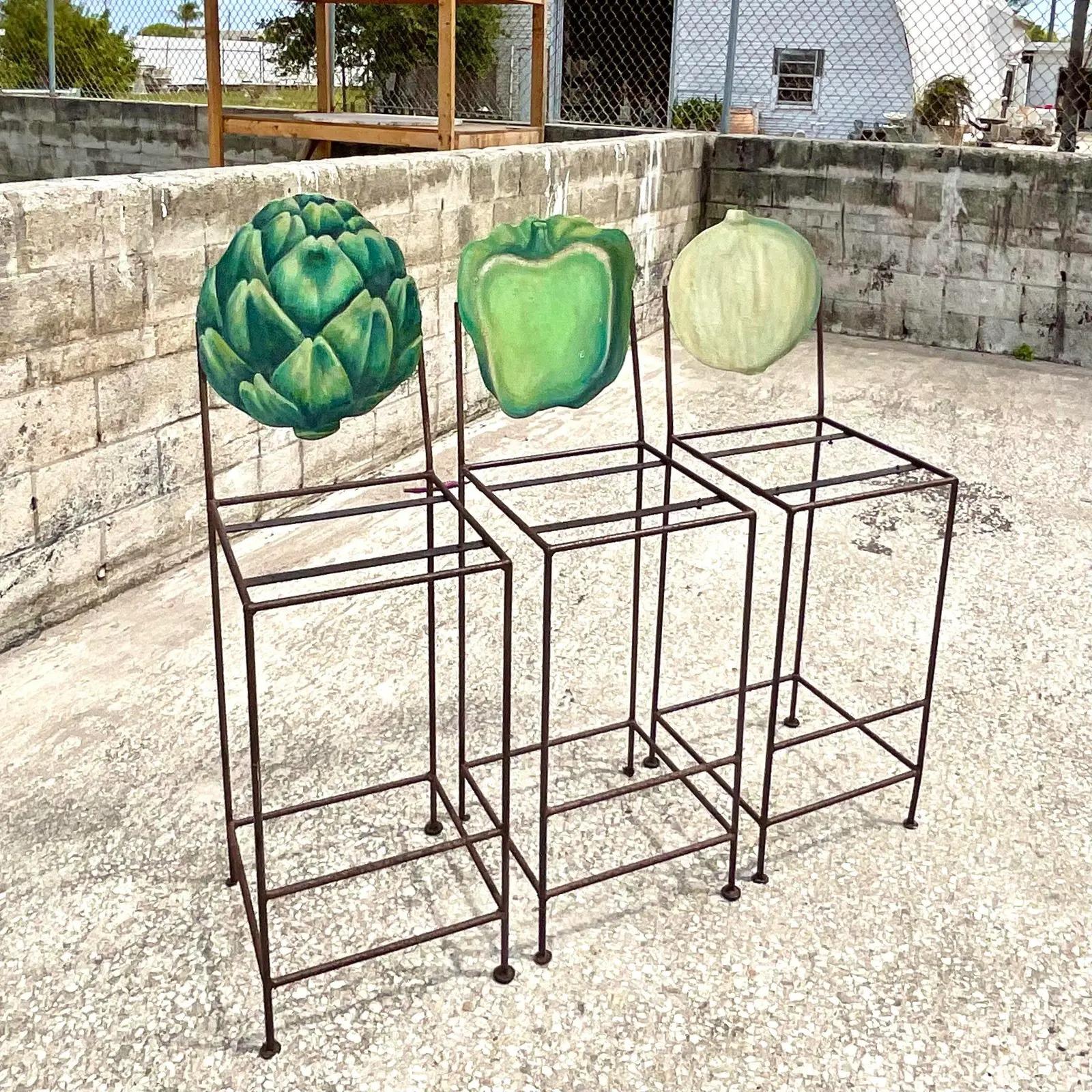 Fantastic set of three hand painted barstools. A charming collection of fresh vegetables serve as the back rest for three tall wrought iron seats. Acquired from a Palm Beach estate.