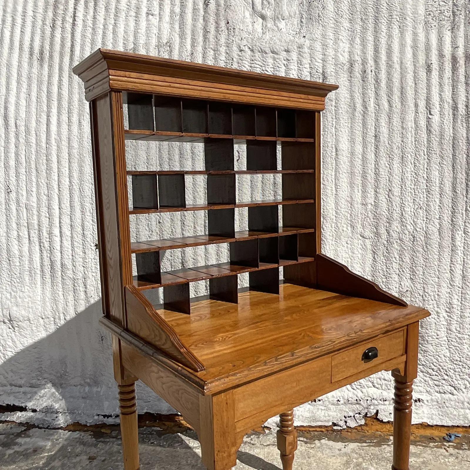 A fantastic vintage Boho PostMaster’s desk. A chic hand turned frame with a large upper cabinet. Perfect as a writing desk, small hotel check in or collectors cabinet. The charm is endless. You can move around the small partitions to create larger