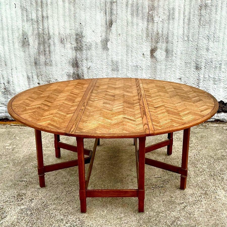 Vintage boho drop-leaf dining table featuring a stunning herringbone-patterned top. Its versatile design includes foldable leaves for space-saving convenience, paired with a warm, rustic finish that complements bohemian and eclectic interiors.