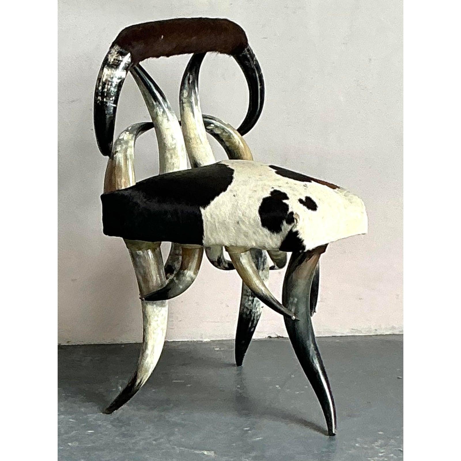 Haz una declaración audaz y distintiva con esta extraordinaria silla vintage Boho Chic de cuerno y piel de vaca. Esta pieza realmente única presenta un diseño cautivador, que incorpora cuernos auténticos para formar tanto el llamativo respaldo como