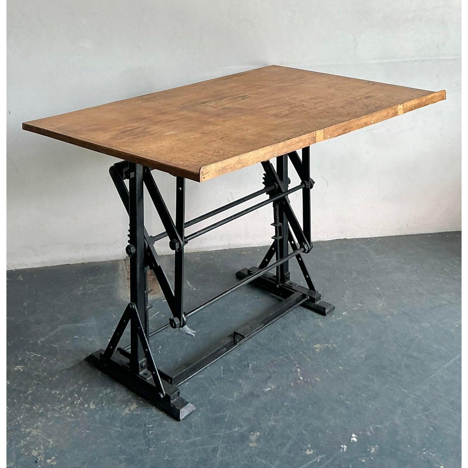Discover this exceptional vintage industrial drafting desk, a robust and aesthetically compelling piece that marries form with unparalleled function. Originating from a bygone era of meticulous craftsmanship, this desk features a sturdy iron base