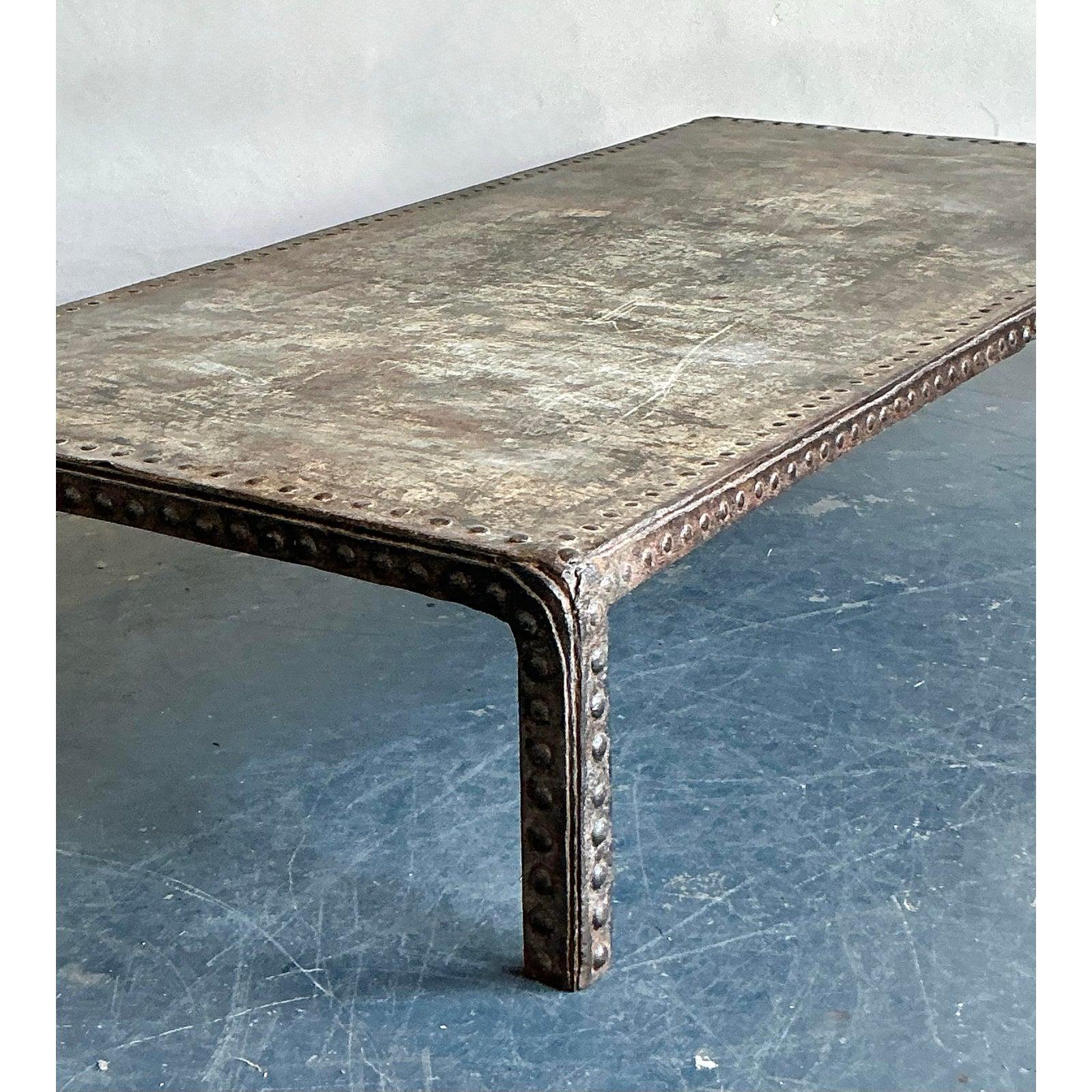 Esta singular mesa de centro vintage combina sin esfuerzo el encanto bohemio con una robusta estética industrial. Con un intrigante acabado envejecido y un distintivo ribete de clavos en los bordes, cuenta una historia de carácter y artesanía. Su