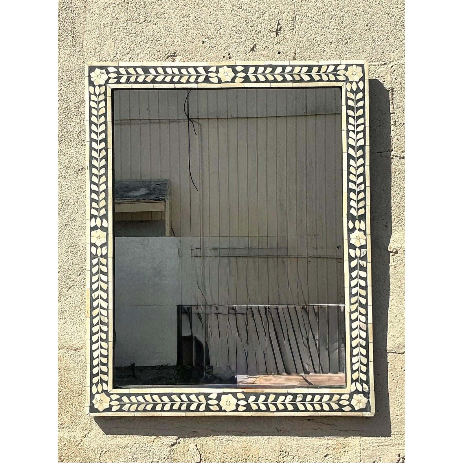 Ce superbe miroir vintage présente un cadre en incrustation d'os travaillé à la main, mettant en valeur un élégant motif de fleurs et de vignes sur un riche fond noir. La fabrication artisanale et le design intemporel créent un contraste saisissant,