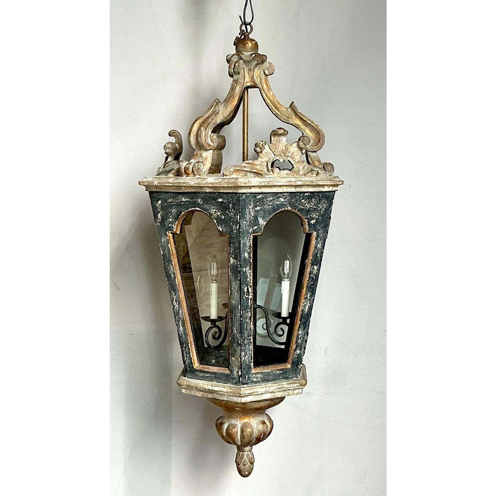 Diese imposante Hängelaterne im Vintage-Stil ist ein Musterbeispiel für traditionelles italienisches Design und besticht durch ihre architektonische Präsenz und gealterte Eleganz. Die aus handgeschnitztem Holz gefertigte und mit aufwändigen