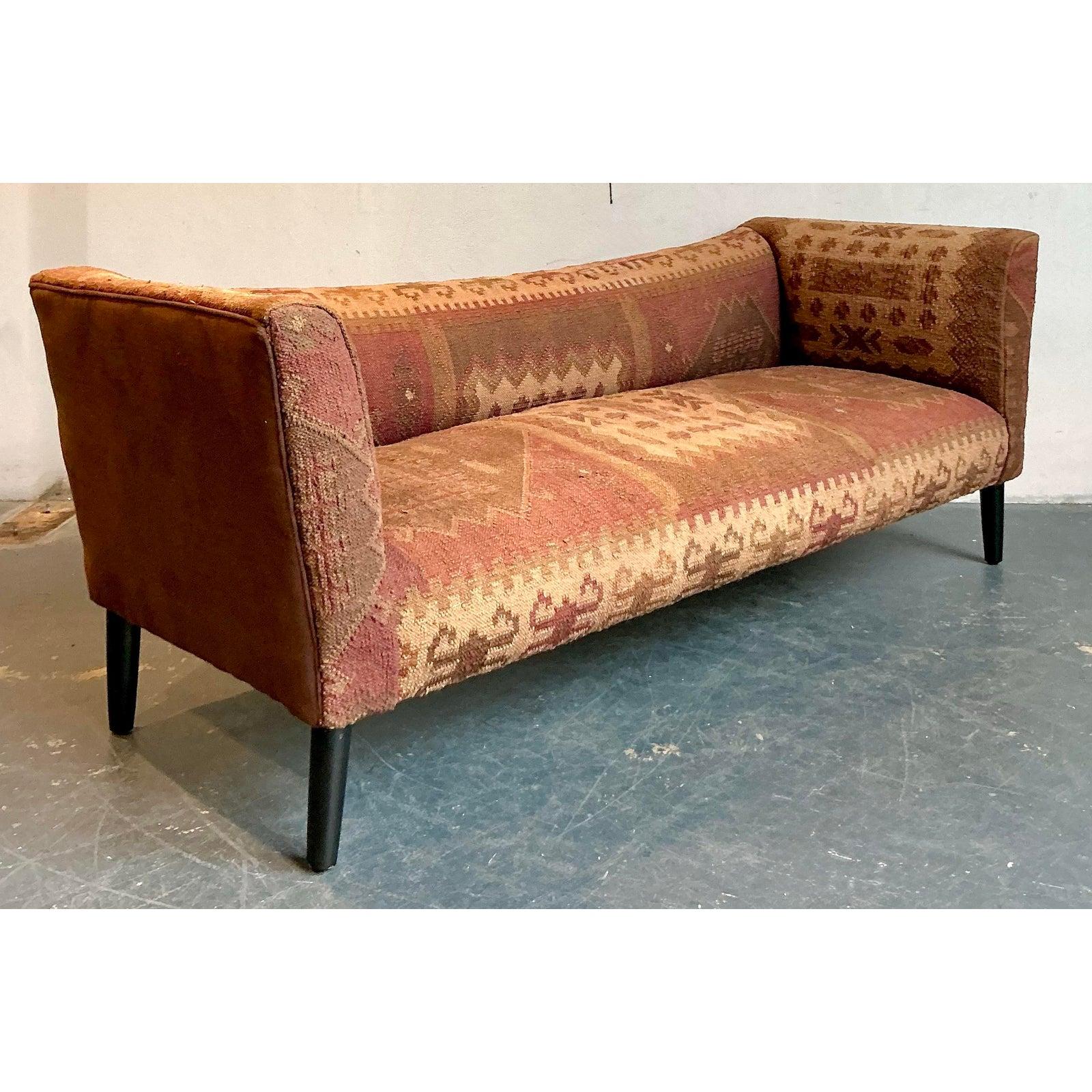 Atrévete con este sofá Boho Kilim vintage único, una pieza llamativa que combina el arte global con una forma inspirada en el centro del siglo XX. Este banco de perfil bajo está expertamente tapizado en una rica tela Kilim tejida a mano, con una