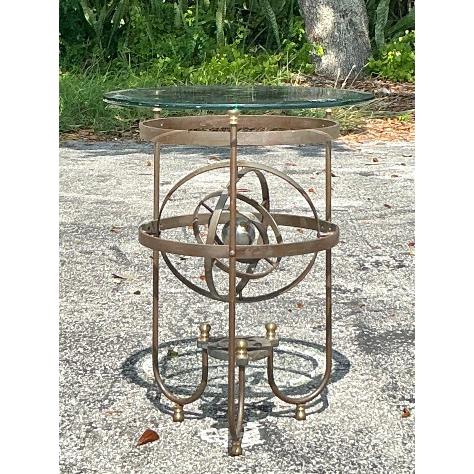 Introduce a captivating blend of celestial intrigue and artistic design into your home with this unique Vintage Boho Kinetic Sphere Side Table. Crafted with a fascinating patinated metal frame, its most striking feature is the central kinetic
