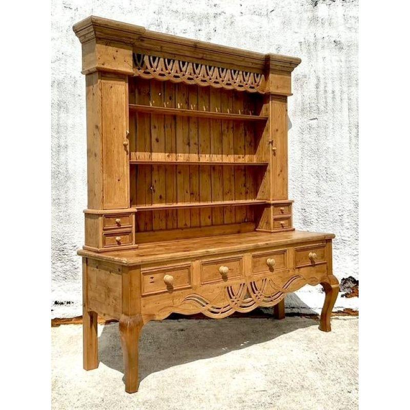 Infuse your home with unparalleled rustic charm and artisanal beauty with this magnificent vintage knotty pine carved hutch. Its substantial presence and the warm, inviting glow of natural knotty pine create an immediate sense of welcome, while the