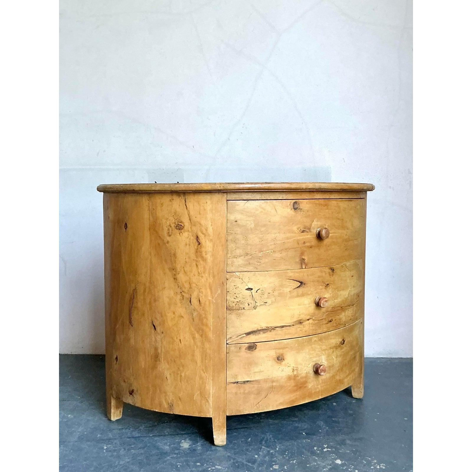 Embrace the rustic charm and unique character of this vintage Boho Chic knotty pine demilune chest of drawers. This delightful piece features a gracefully curved demilune (half-moon) silhouette, crafted from beautifully aged knotty pine that