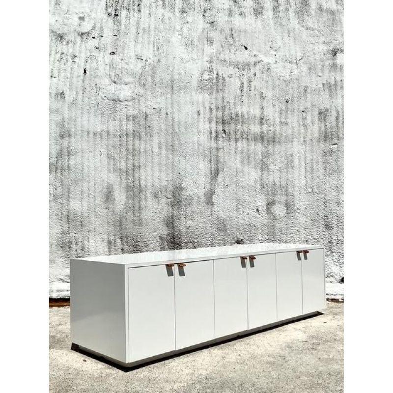 Experience the intersection of architectural minimalism and bohemian warmth with this exceptional vintage lacquered credenza. Its impressive 84-inch length and clean, monolithic form create a dramatic horizontal anchor for any sophisticated