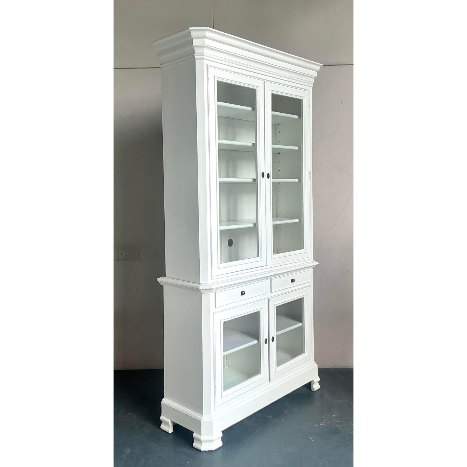 Discover this charming vintage lacquered display cabinet, an exquisite piece that effortlessly blends Boho and Shabby Chic aesthetics from the mid-20th century. Finished in a delightful white lacquer, this cabinet features a classic silhouette with