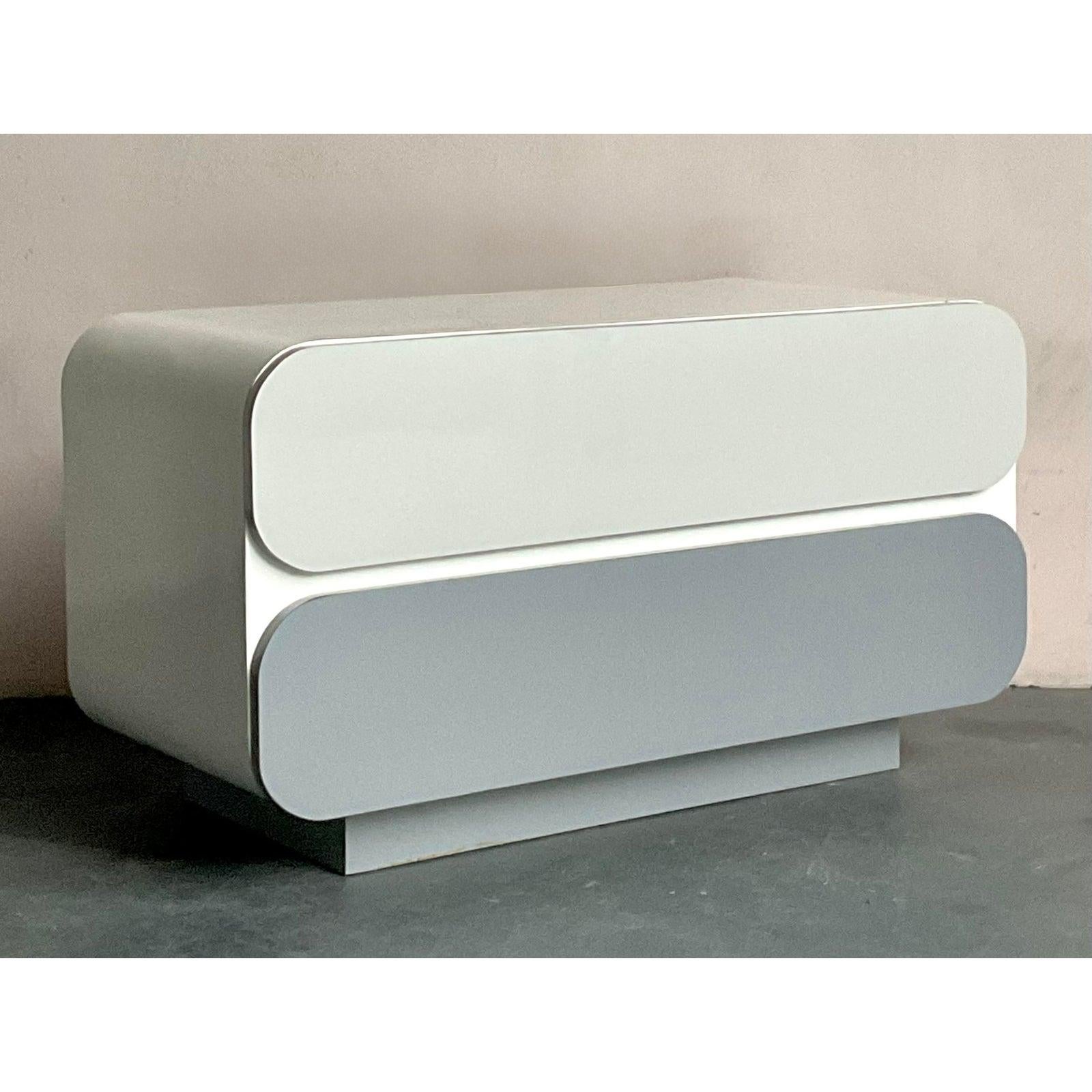 Scopri il fascino di un design essenziale con questa cassettiera vintage in laminato, un superbo esempio di estetica Mid-Century Modern con un pizzico di influenza Boho. Realizzato con linee pulite e una sorprendente finitura bicolore bianca e