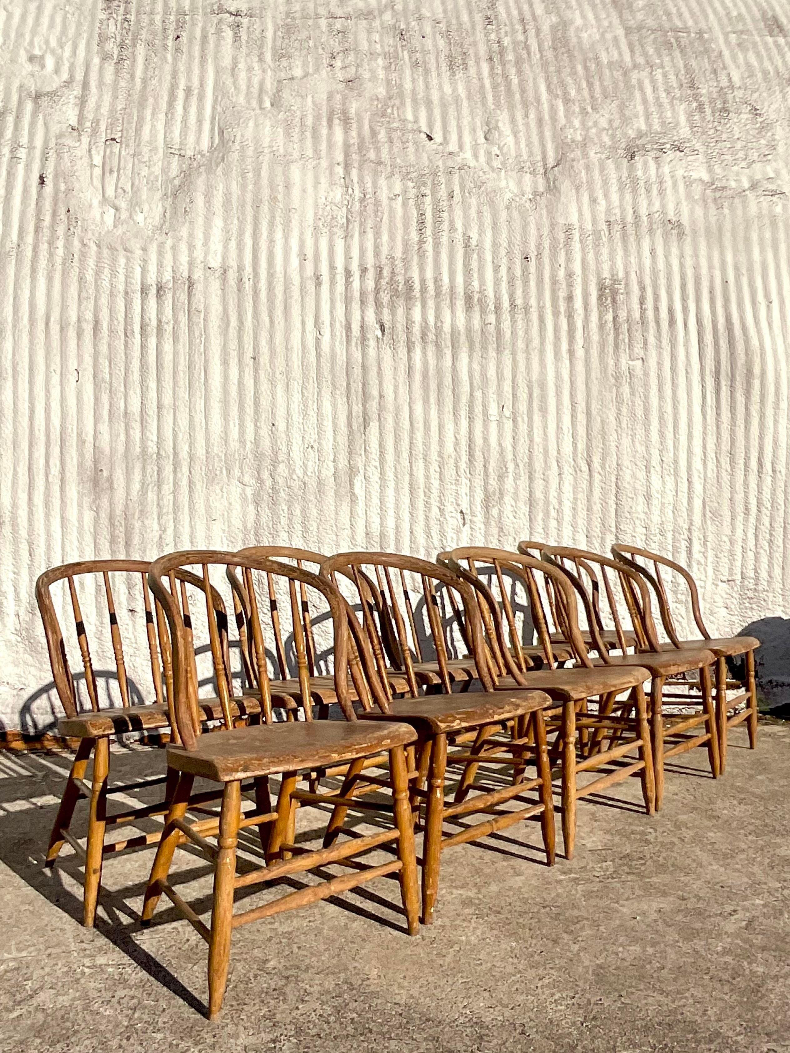 A magnificent set of 10 vintage Primitive dining chairs. A chic Windsor style frame with hand turned spindle legs. Each chair has a bent arched back and arms. Coordinating table also available on my page. Acquired from a Historical Florida estate.