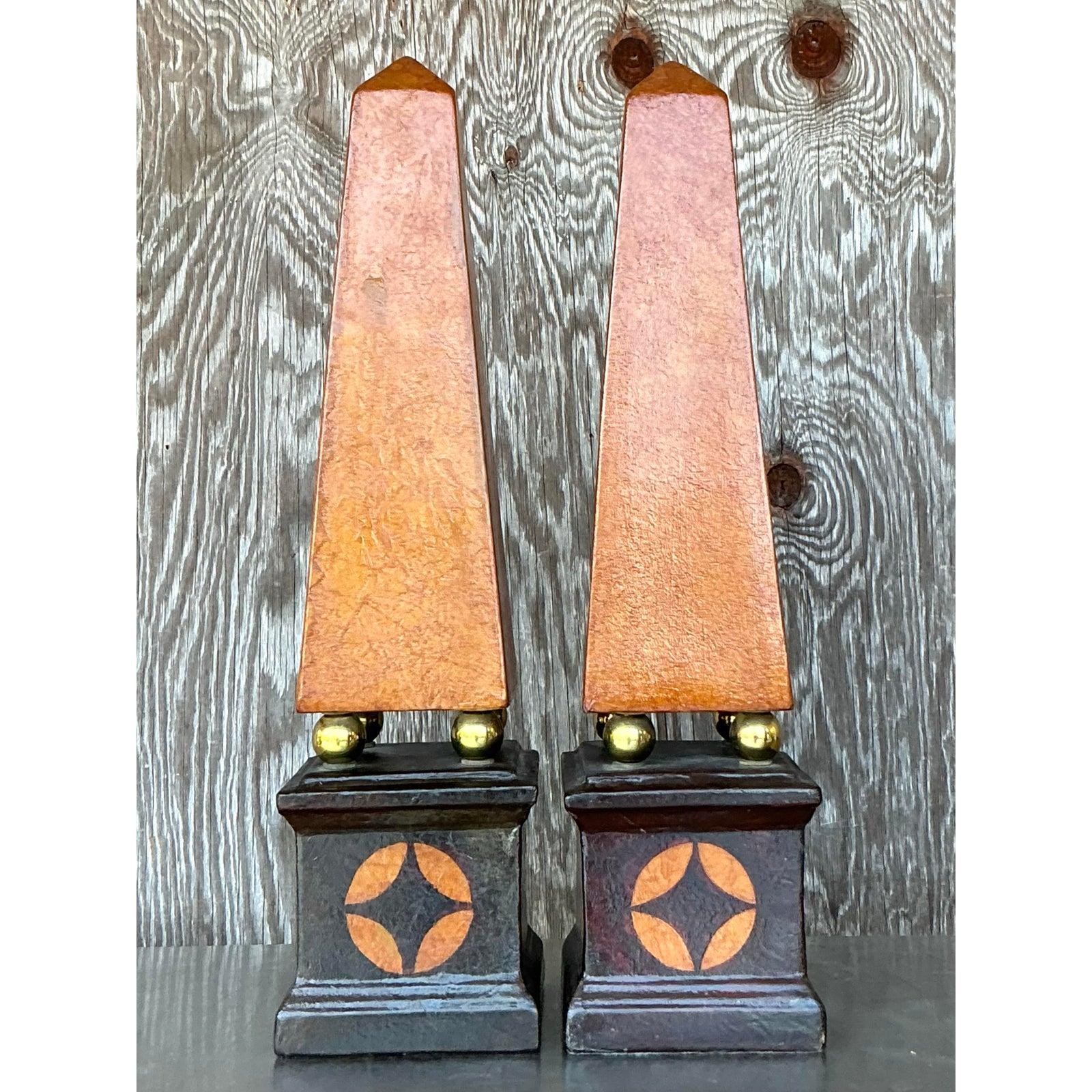 Ajoutez une déclaration architecturale à votre espace avec cette superbe paire d'obélisques en cuir boho vintage. Ces pièces décoratives remarquables présentent une riche finition en cuir aux tons chauds, magnifiquement contrastée par des sphères en