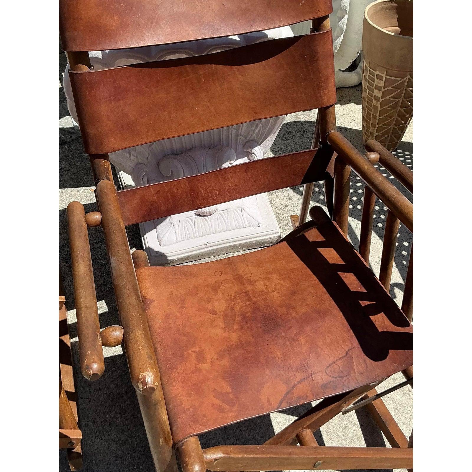 Questa splendida coppia di sedie a dondolo Campaigner in stile boho vintage unisce un'eleganza robusta a un comfort senza tempo. Realizzate con una robusta struttura in legno, queste sedie sono caratterizzate da sedute e schienali in pelle marrone,