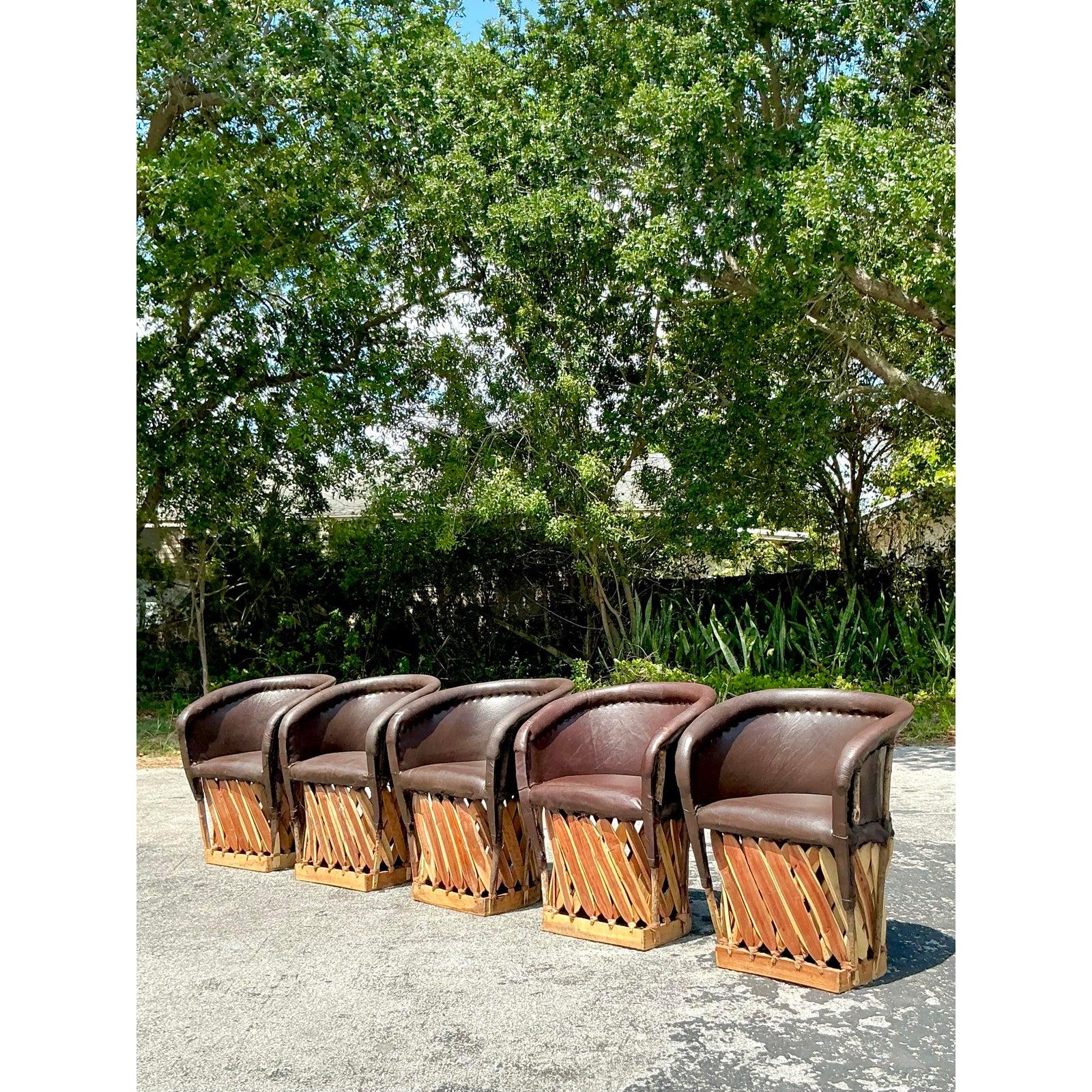 Infuse your space with rustic charm and artisanal warmth with this striking set of five Vintage Boho Equipale Chairs. Handcrafted in the traditional Mexican style, each chair features a richly patinated leather seat and curved backrest, gracefully