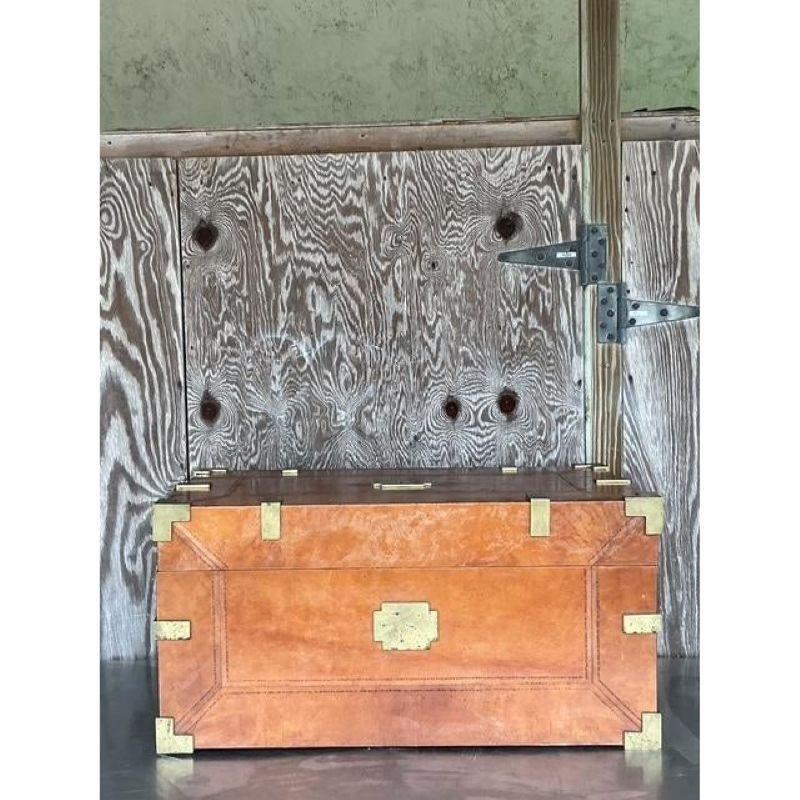 Evoke a sense of timeless adventure and sophisticated heritage with this handsome vintage campaign trunk. Meticulously wrapped in rich, cognac-hued leather, this piece is beautifully accented with gleaming brass hardware, robust corner protectors,