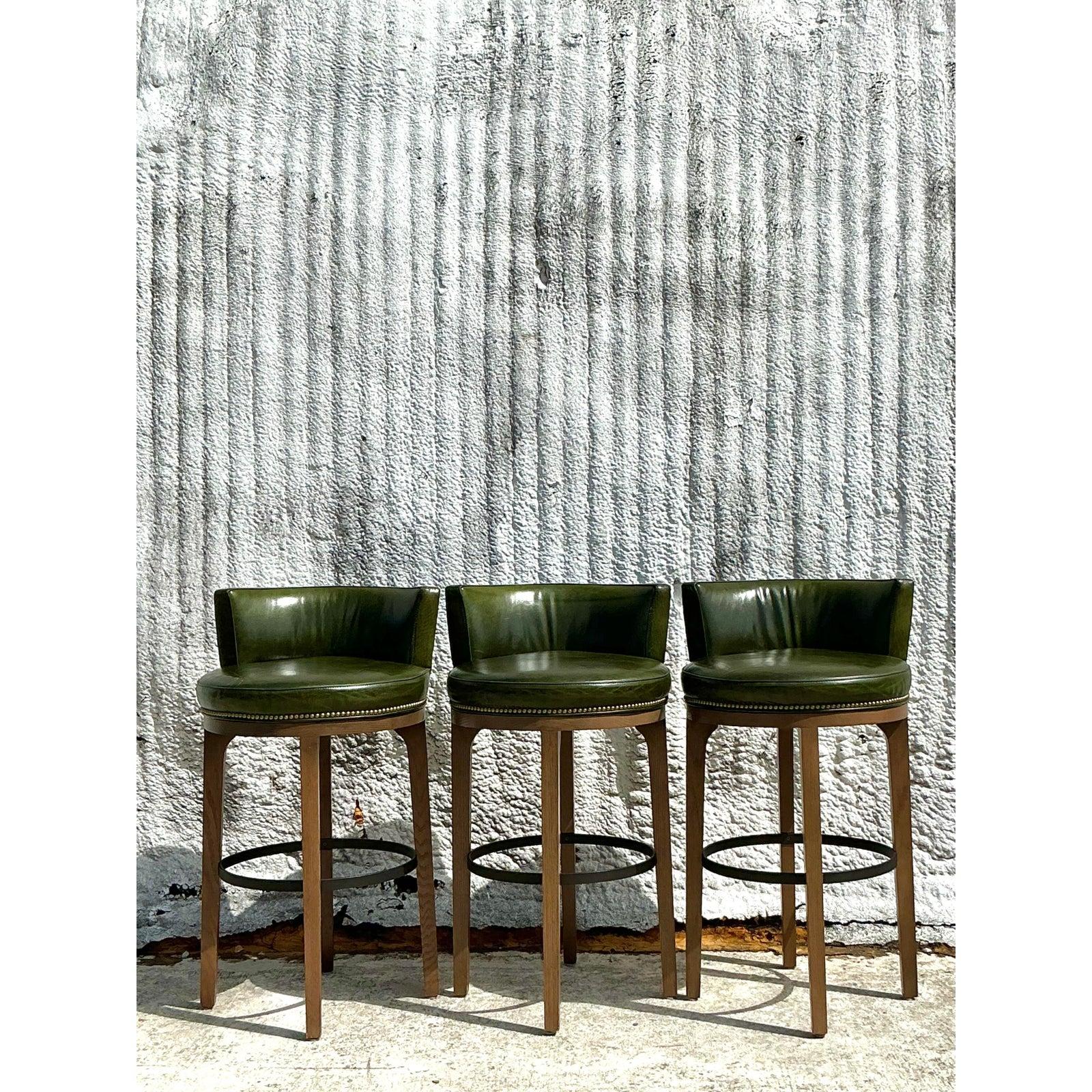 Elevate your space with this exquisite set of three Vintage Boho Lee Industries Swivel Bar Stools, where timeless craftsmanship meets bohemian flair. These stools, crafted by the renowned Lee Industries, feature rich forest green leather upholstery