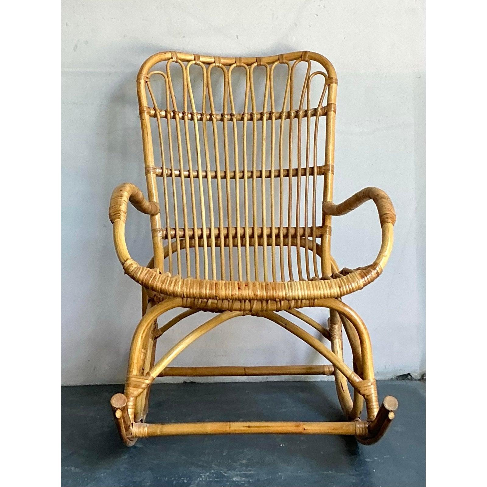 Eleganza rilassata dell'era del Mid-Century Modern con questa affascinante sedia a dondolo vintage. Realizzato in rattan naturale, il suo caratteristico design ad anello e l'ariosa trama aperta evocano un senso di raffinatezza organica,