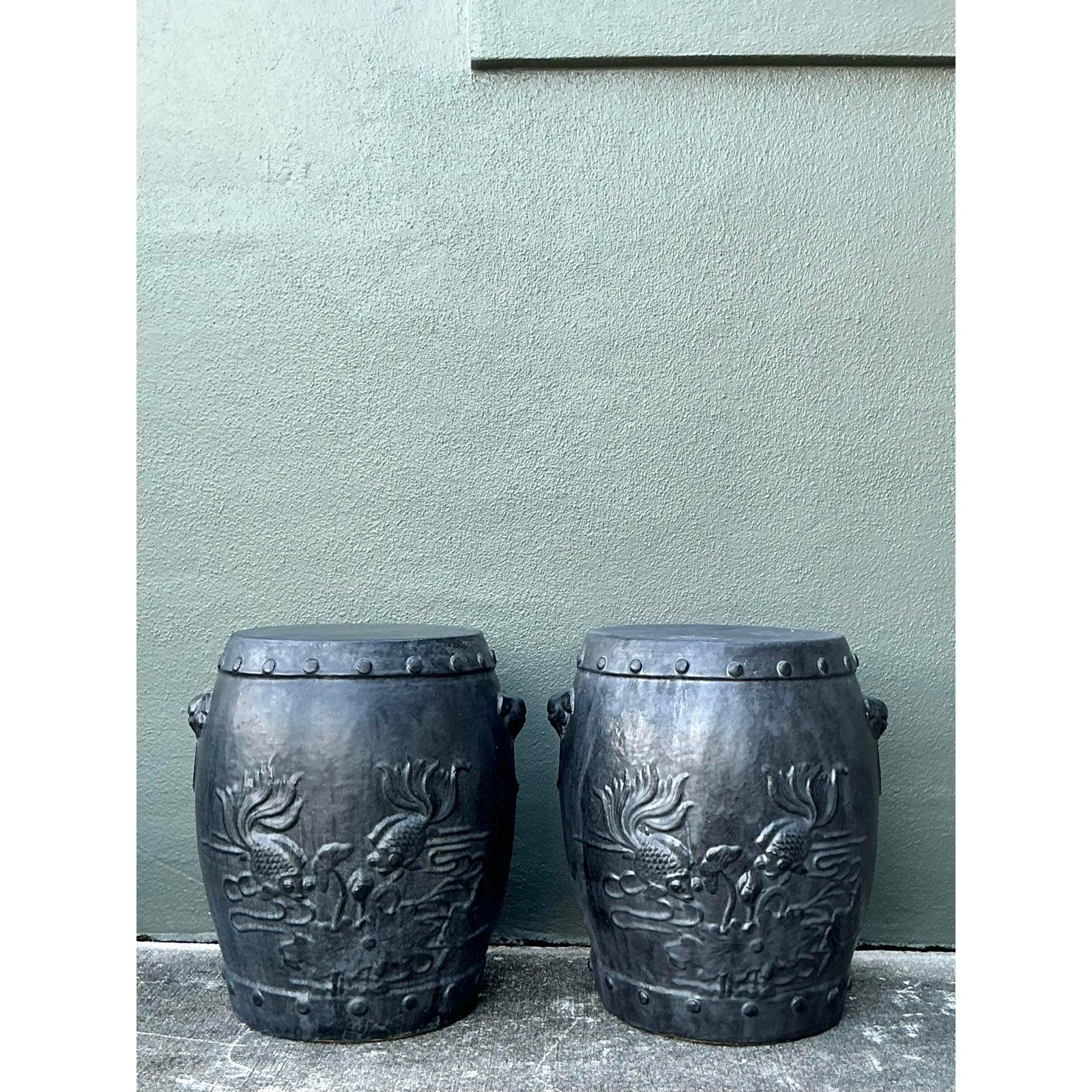 Enraíza tu espacio con la belleza sofisticada y elemental de este par de taburetes de jardín de cerámica vintage. A diferencia de sus homólogos comunes de alto brillo, estos taburetes presentan un raro acabado negro carbón mate que imita el aspecto