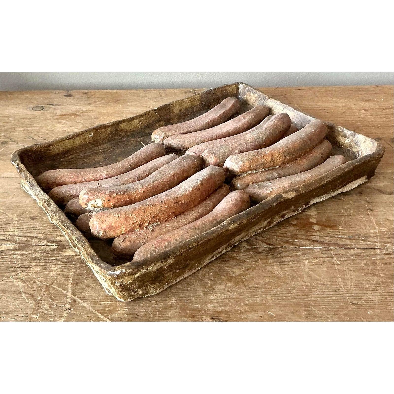 A wonderfully surreal and conversation-starting piece of trompe l'oeil ceramic art, this vintage tray of sausages is a testament to playful, artisanal craftsmanship. Meticulously hand-sculpted, each link is rendered with surprising realism, all