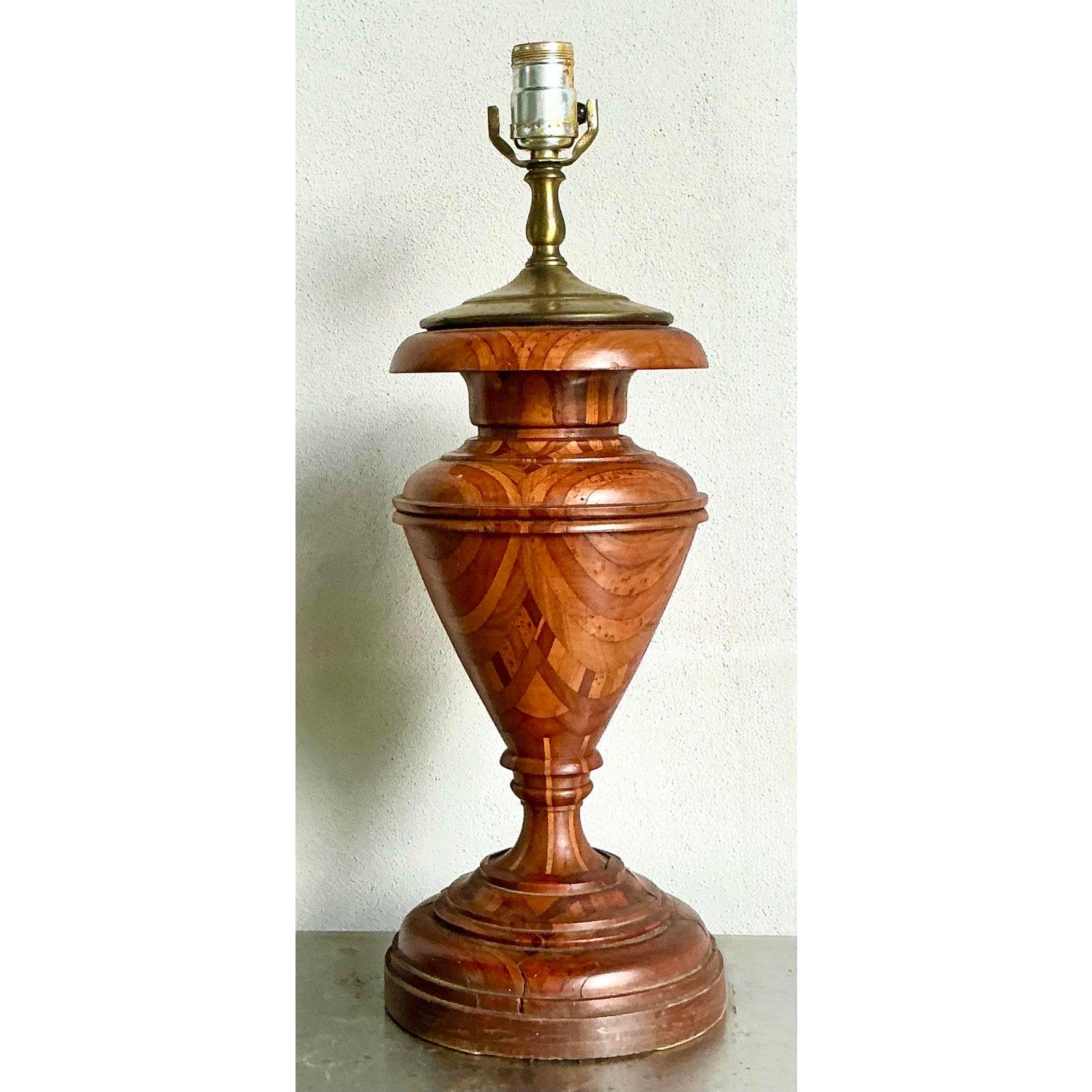 Questa squisita lampada da tavolo vintage è una vera e propria testimonianza di artigianato, caratterizzata da una splendida intarsio e da un legno tornito. Il corpo della lampada presenta intricati motivi a intarsio formati da varie tonalità di