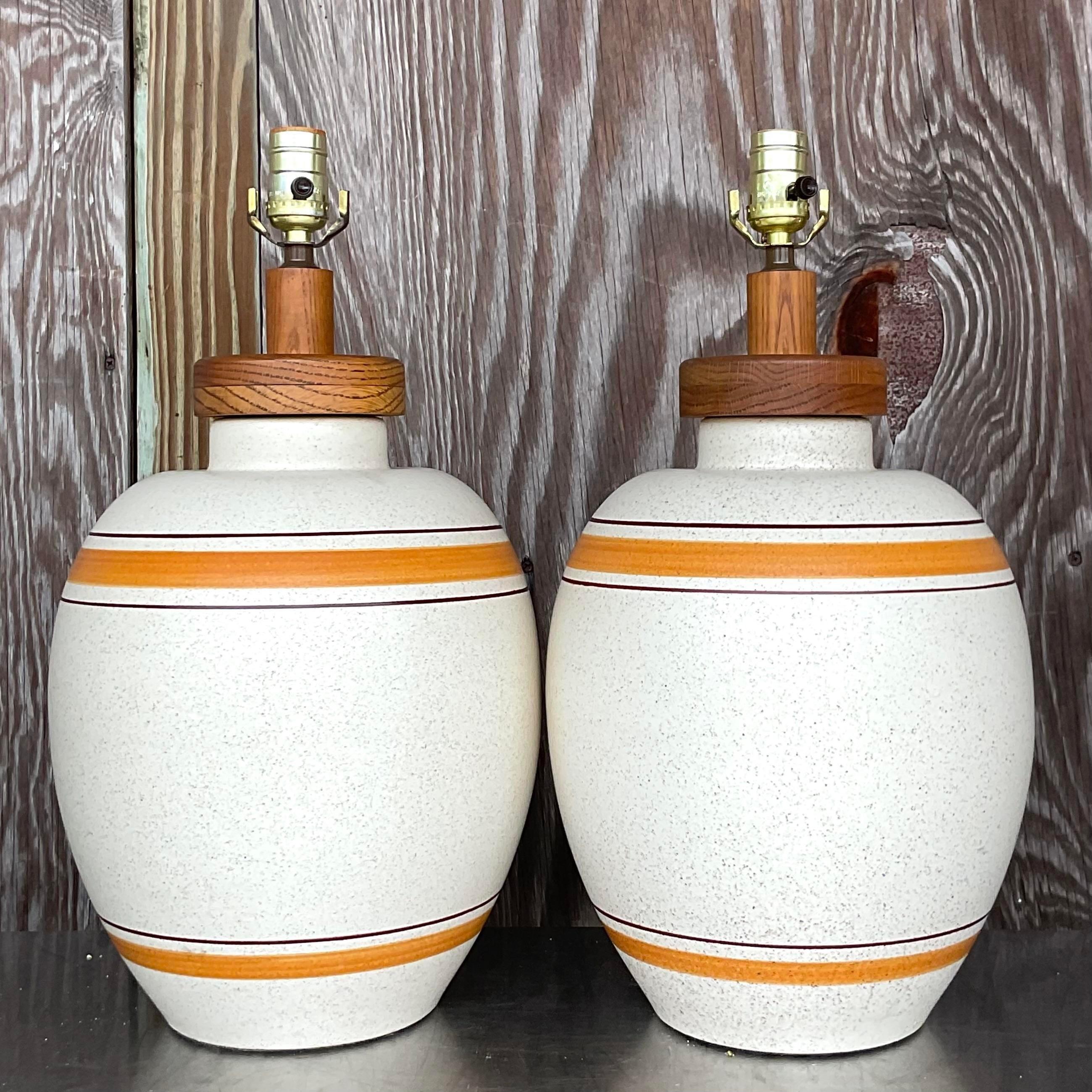 A fantastic pair of vintage Boho table lamps. A gorgeous orange stripe on the neutral body of these matte ceramic lamps. Chic wood hardware. Acquired from a Palm Beach estate.