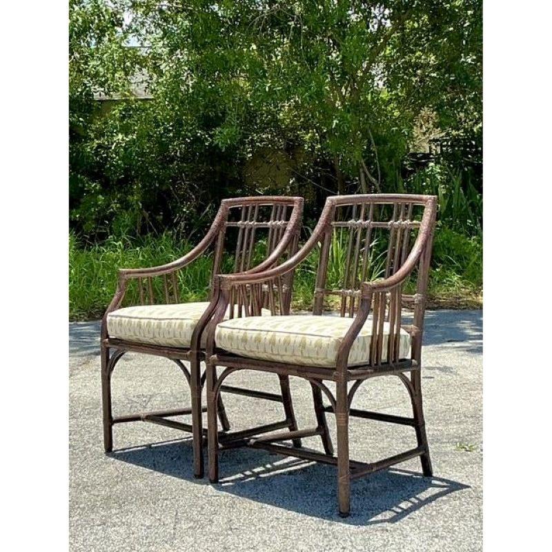 Capture the essence of timeless California style with this exquisite pair of vintage armchairs by the renowned McGuire. Masterfully crafted from richly stained rattan, these chairs feature the iconic grid or 