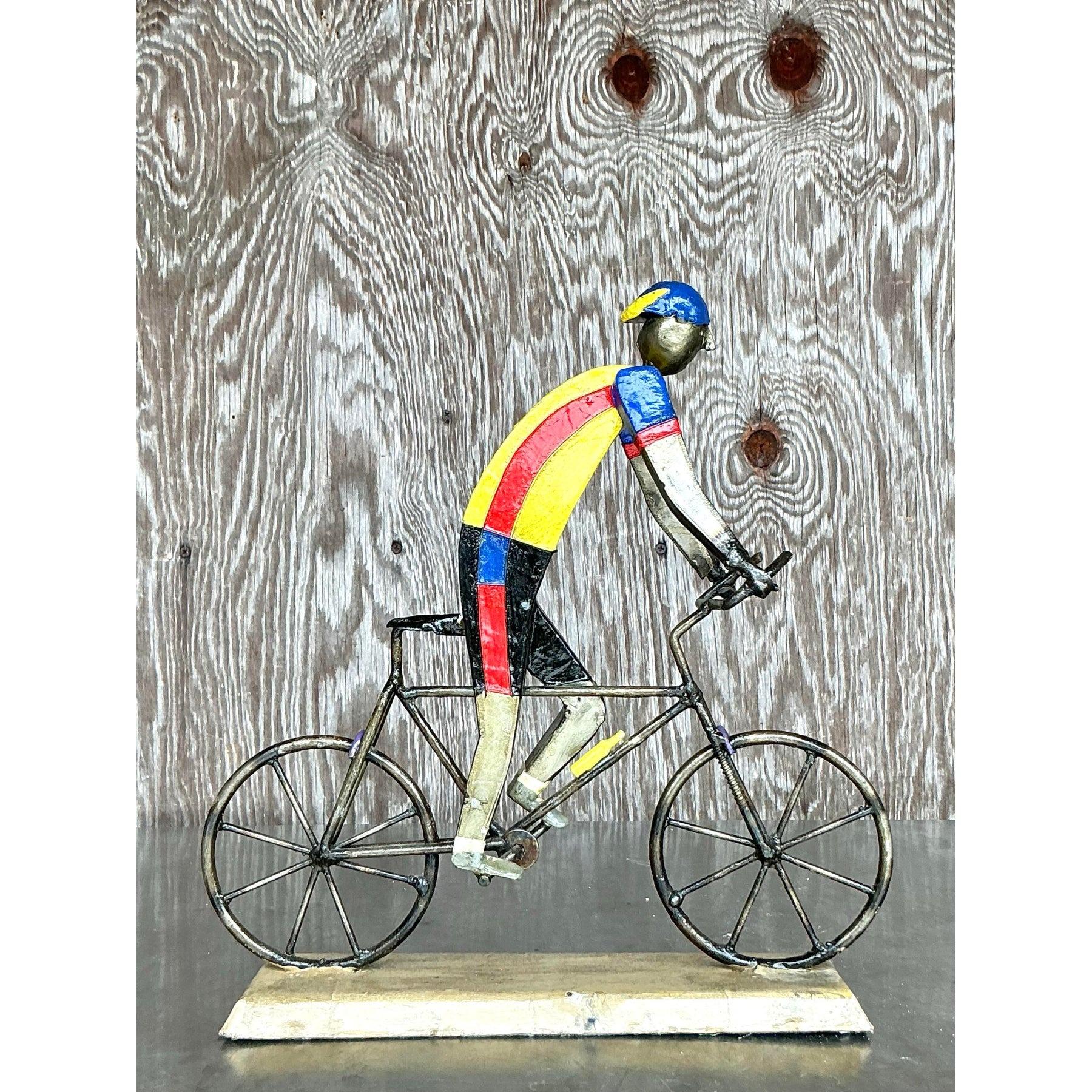 Cette sculpture métallique vintage unique capture magnifiquement l'essence d'un cycliste en mouvement. Fabriquée à la main avec un travail de métal complexe et peinte dans des teintes vibrantes de jaune, de rouge et de bleu, cette pièce respire