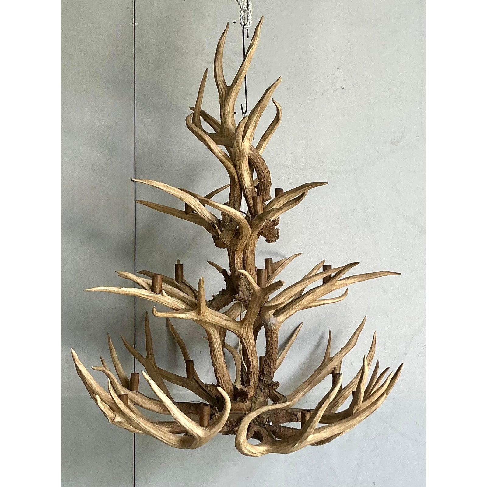 Ce lustre monumental en bois de cerf vintage attire l'attention et évoque l'esprit de la grande loge américaine. Ce luminaire est une composition magistrale de bois de cervidés perdus naturellement. Il est tissé de manière complexe pour créer une