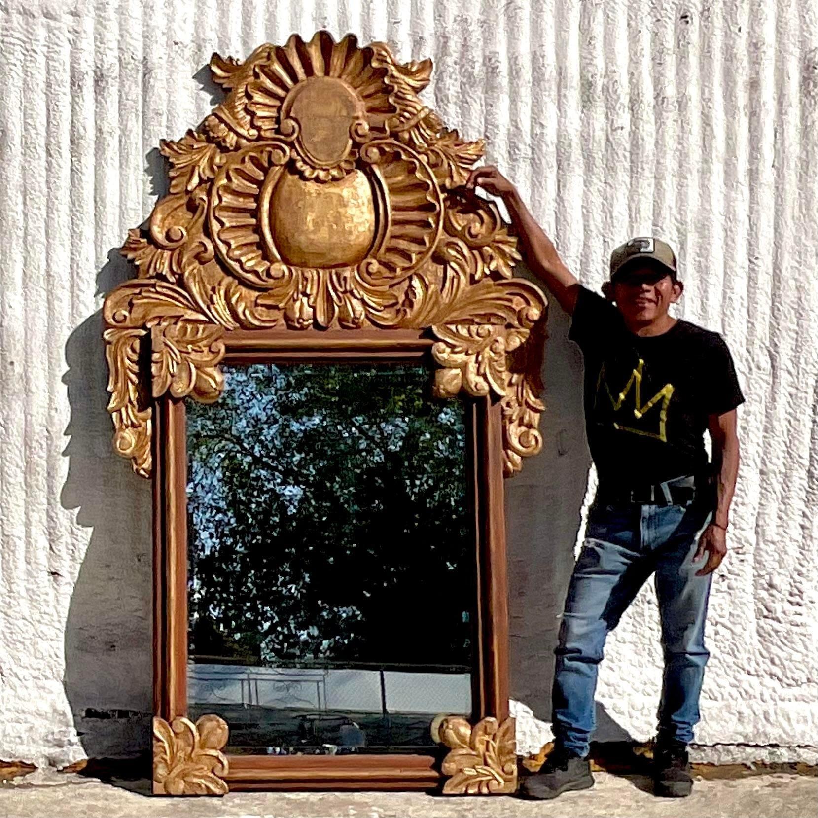 A fantastic vintage Boho wall mirror. A chic hand carved frame in a warm gilt finish. Monumental in size and drama. Acquired from a Palm Beach estate.